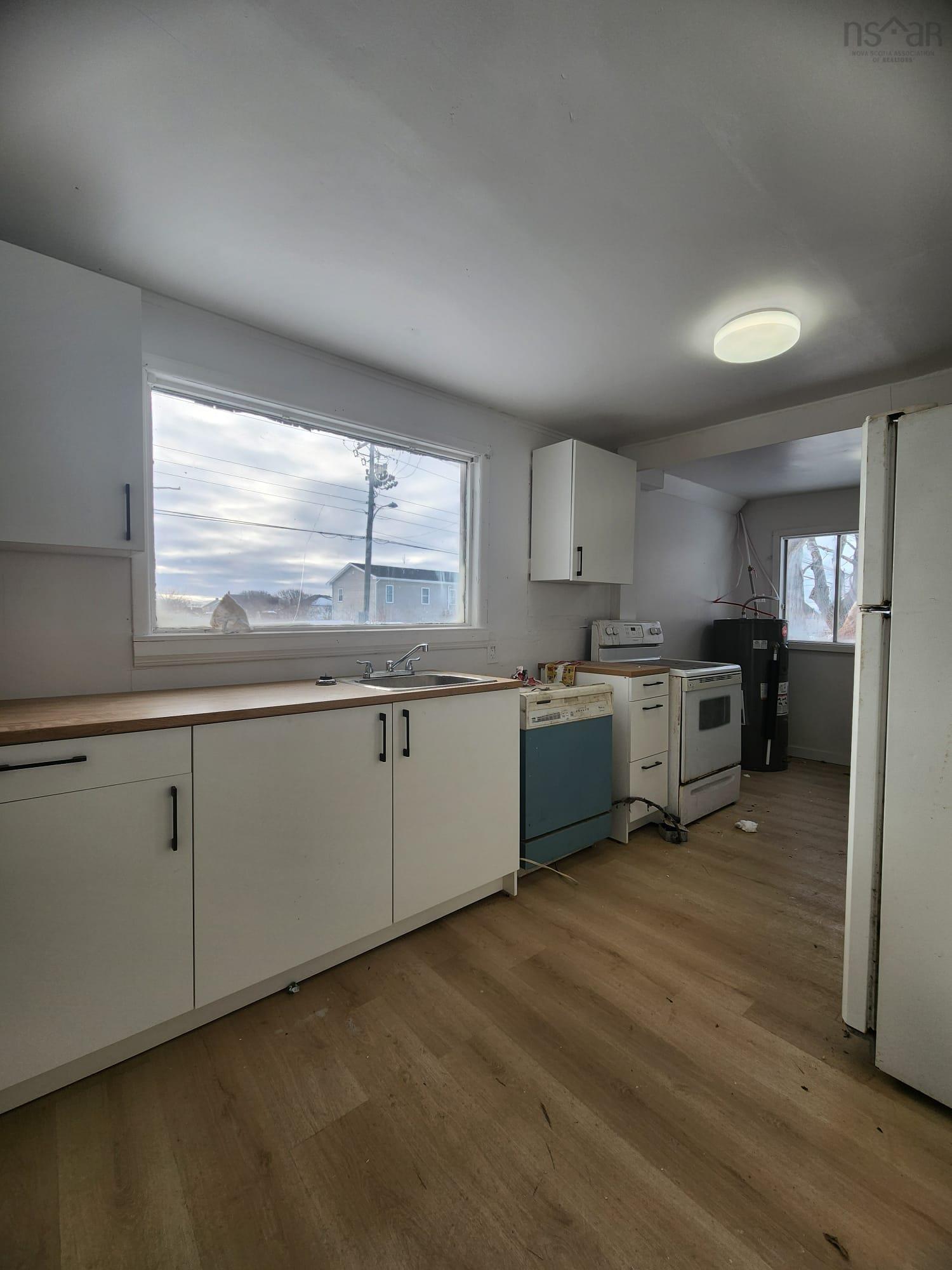 Kitchen featuring white cabinets, white appliances, light wood-style floors, and light countertops