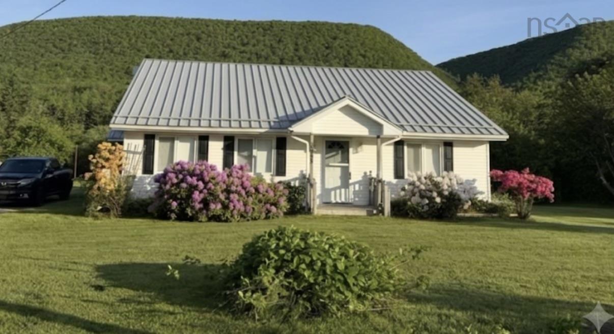 White siding home featuring a metal roof and black window shutters