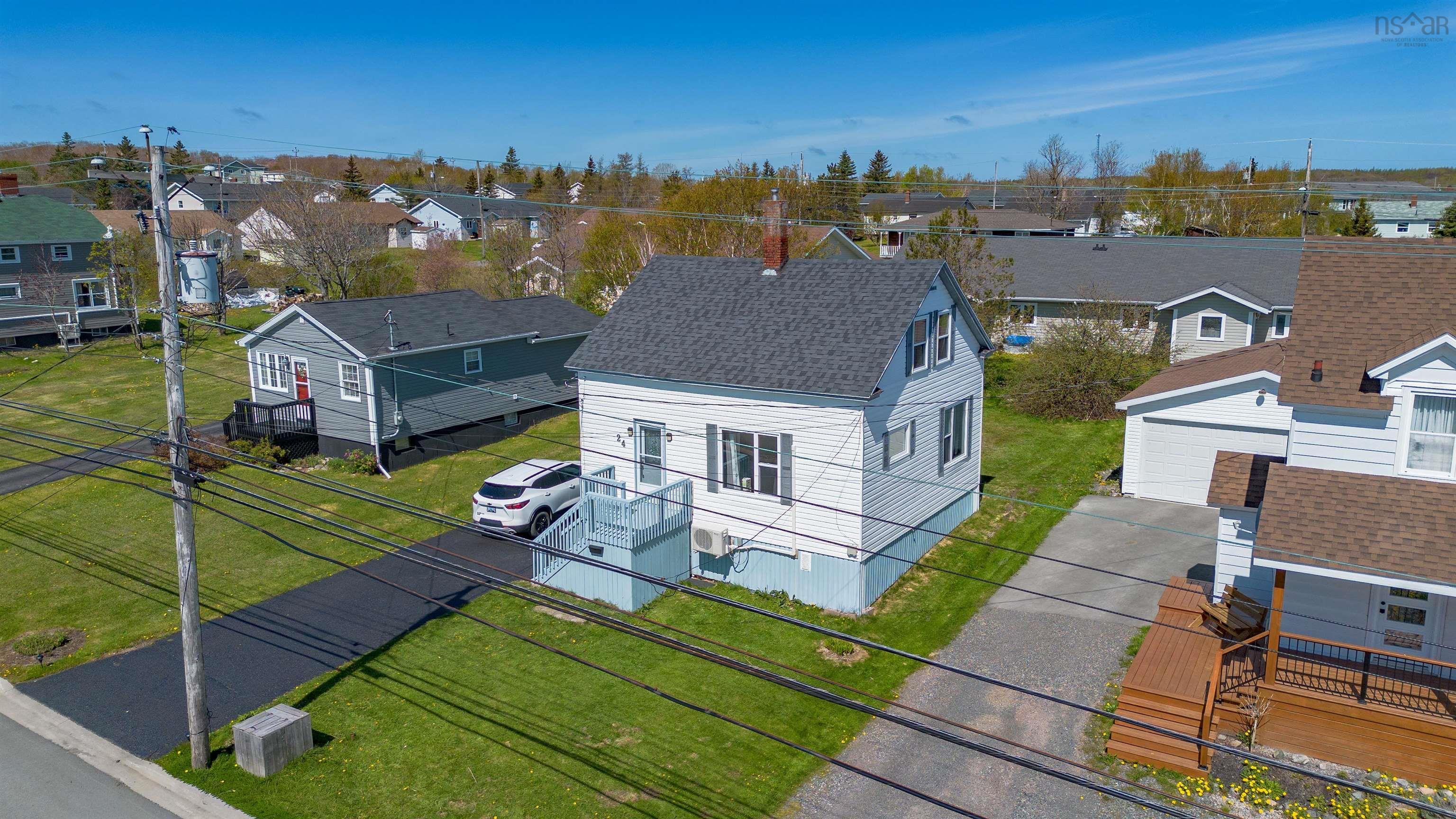 White-sided residence featuring a gray shingle roof, paved driveway, and established green lawn
