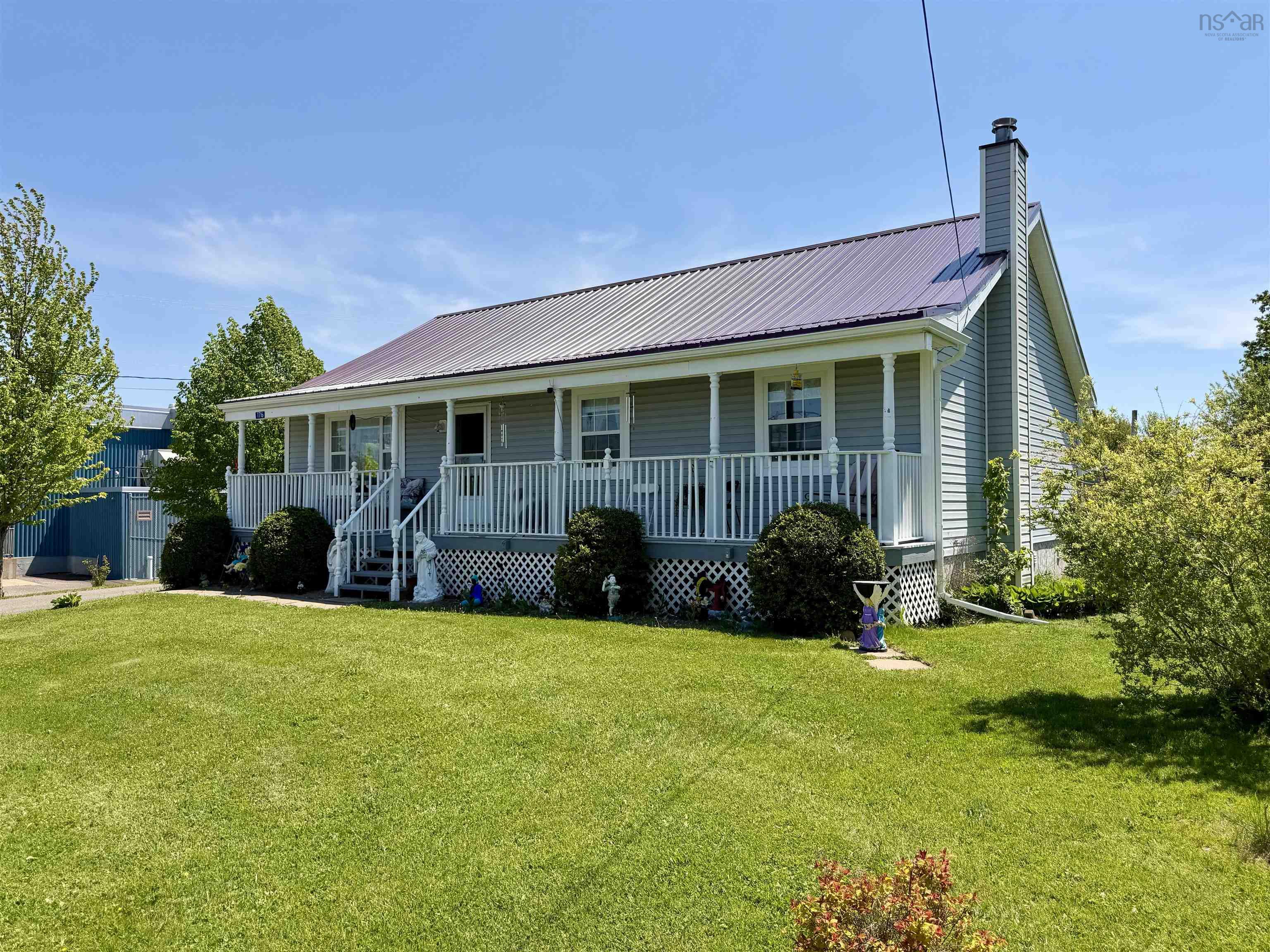 Light gray siding exterior with a wraparound front porch featuring white railings