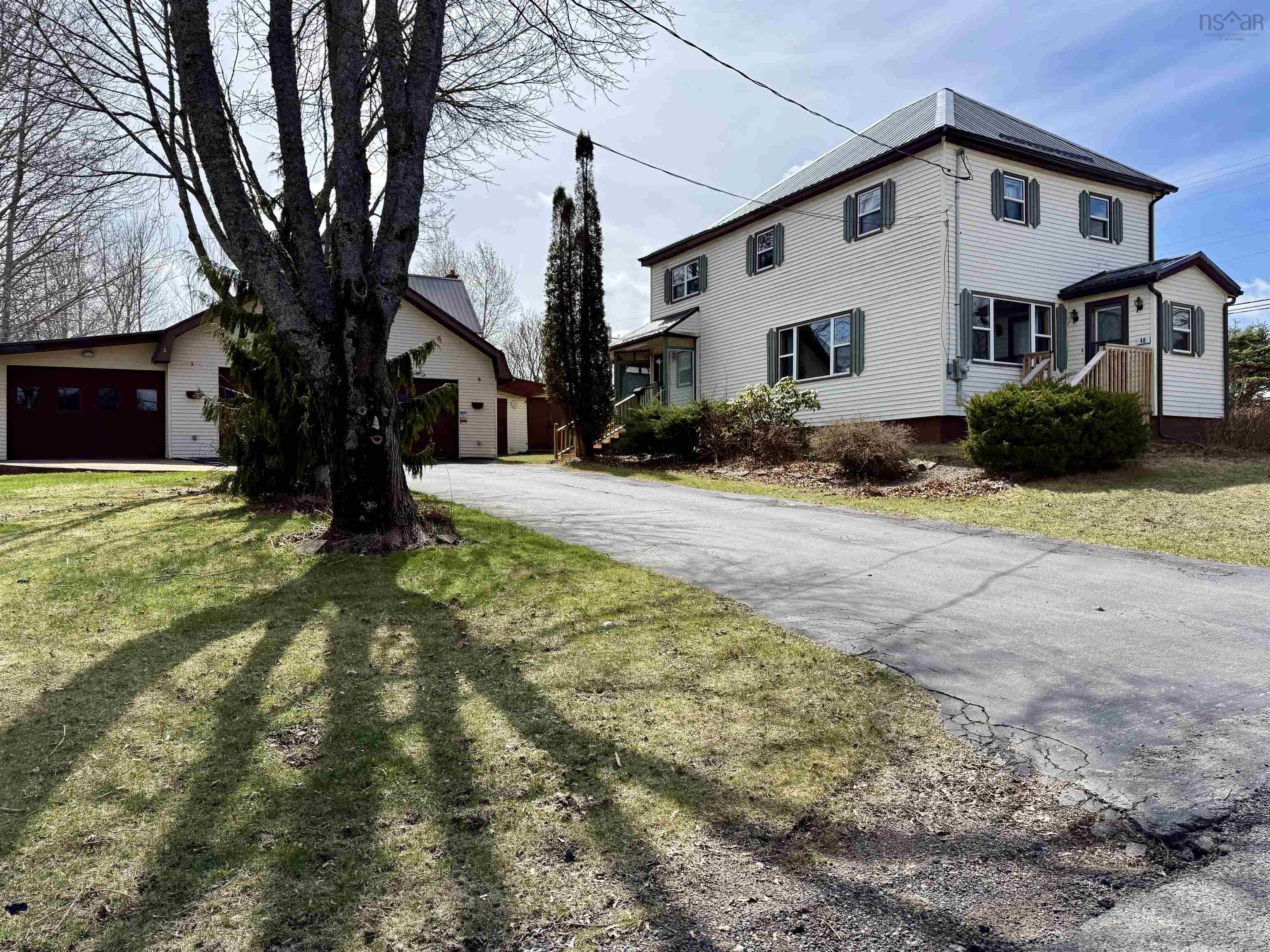 View of front of property with an outdoor structure, a garage, and a metal roof