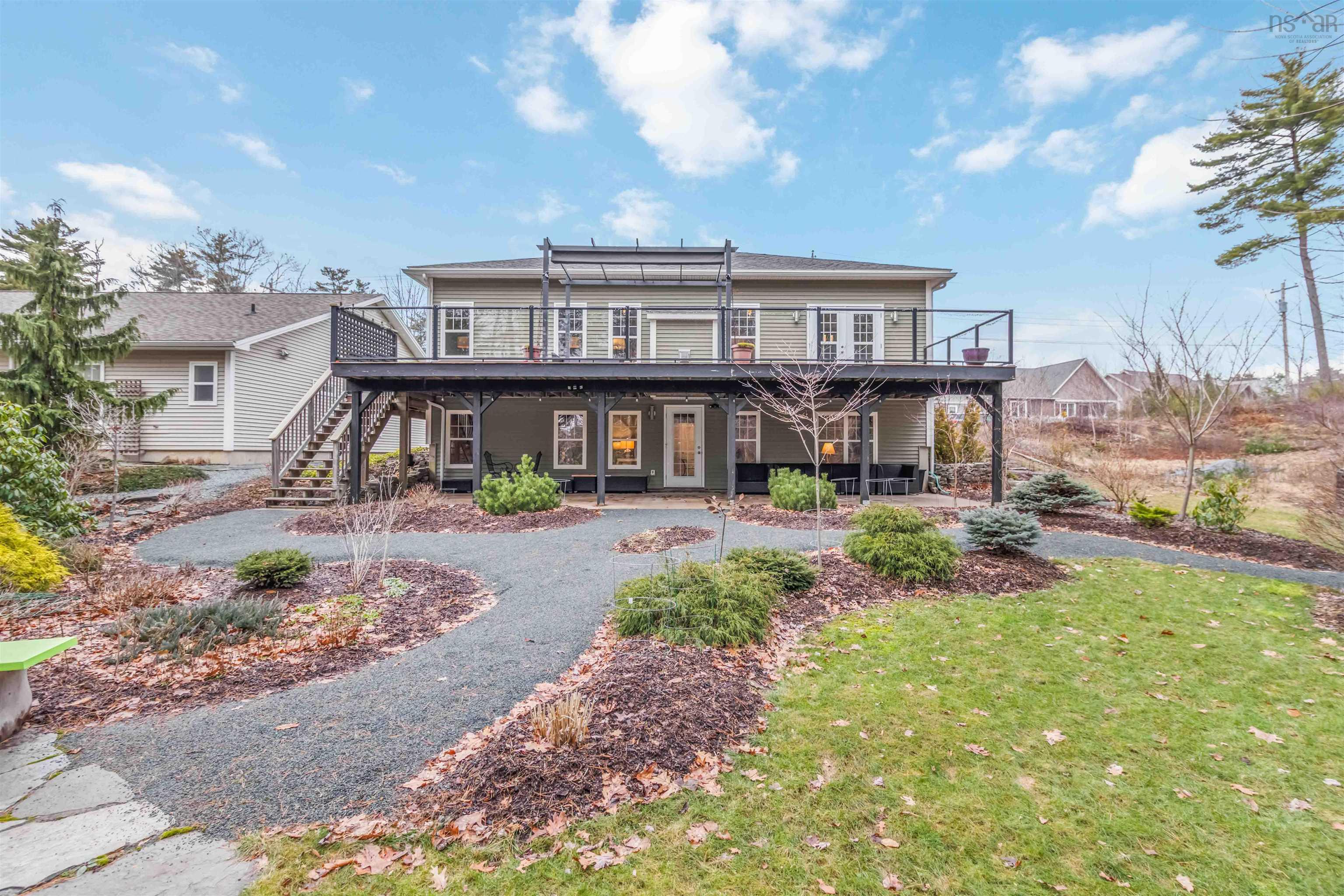 Back of property with a wooden deck, a lawn, and a patio area