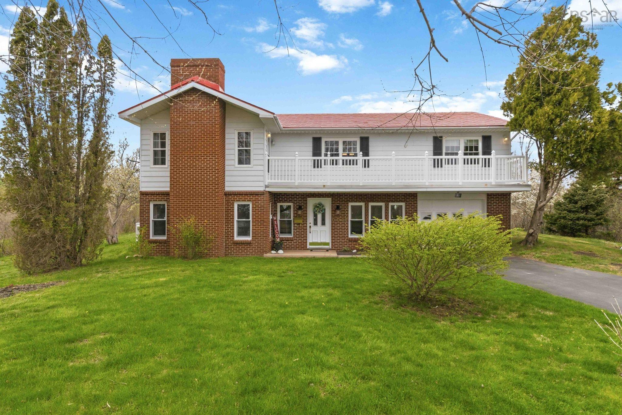 Two-story residence featuring a red roof, white siding, and a prominent brick chimney