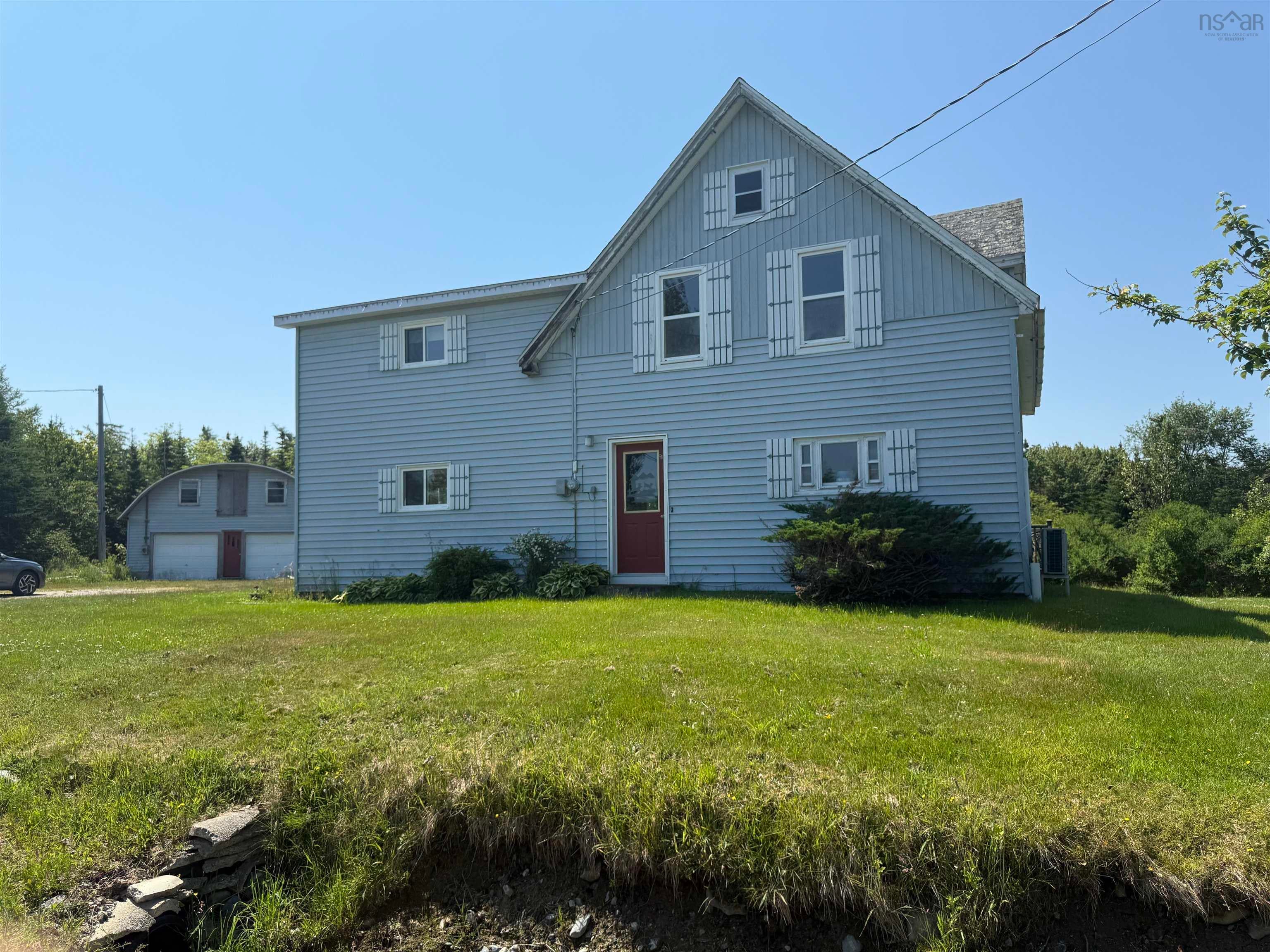 Two-story light blue siding residence with a red entry door and white louvered shutters