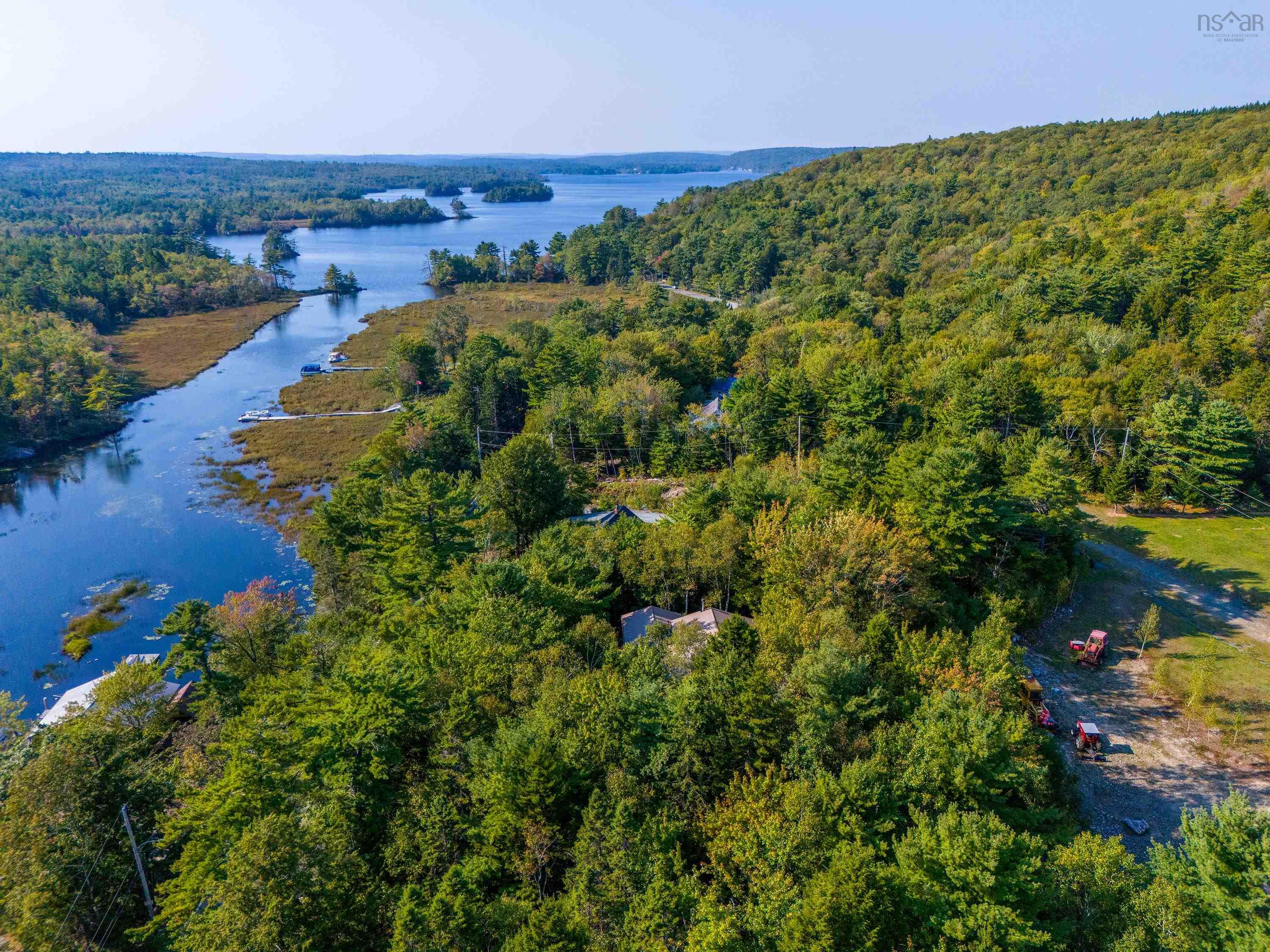 Aerial view showcasing the property's setting amidst a lush, wooded landscape and a tranquil body of water