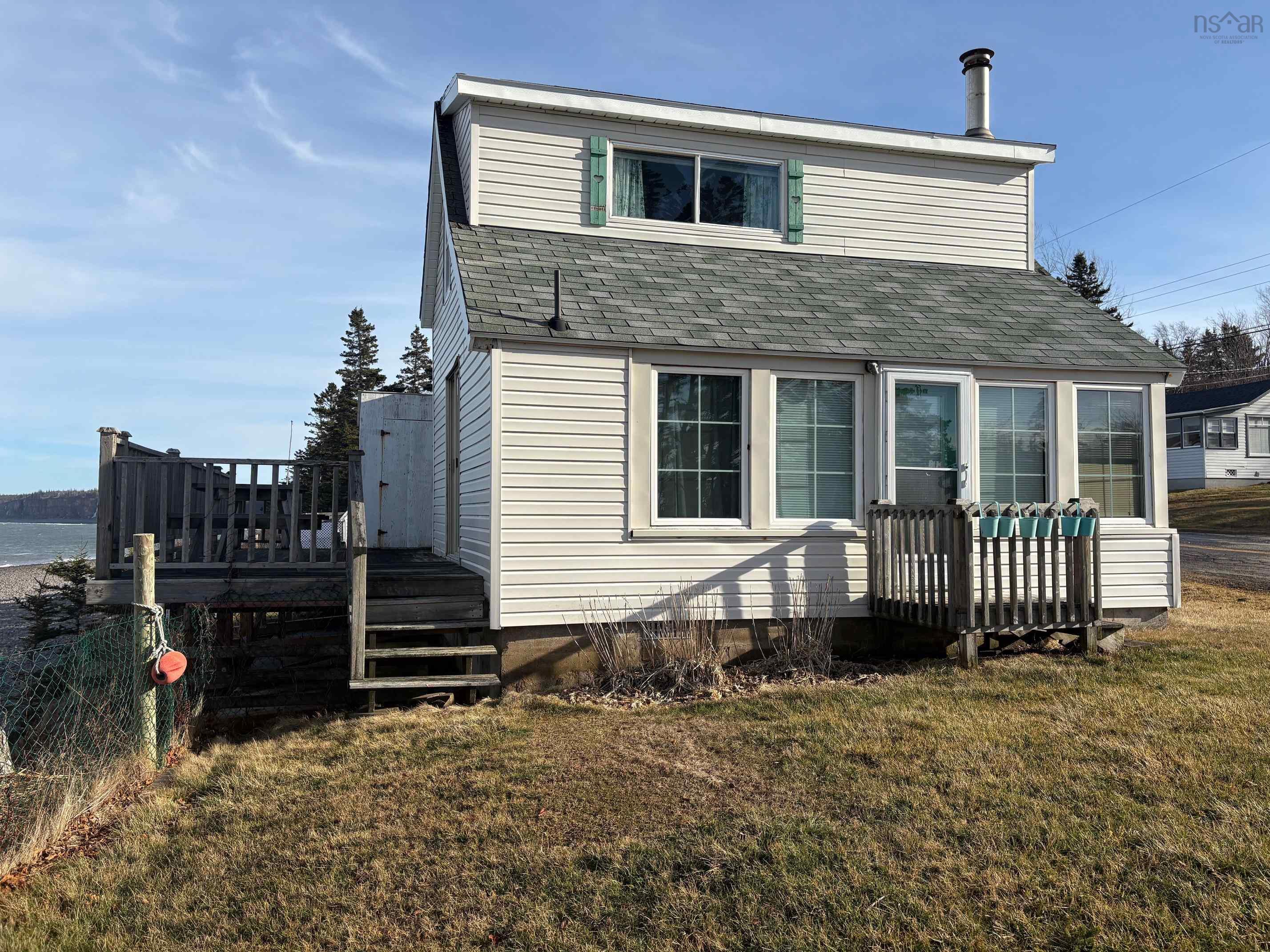 Back of property featuring a deck, a yard, and roof with shingles