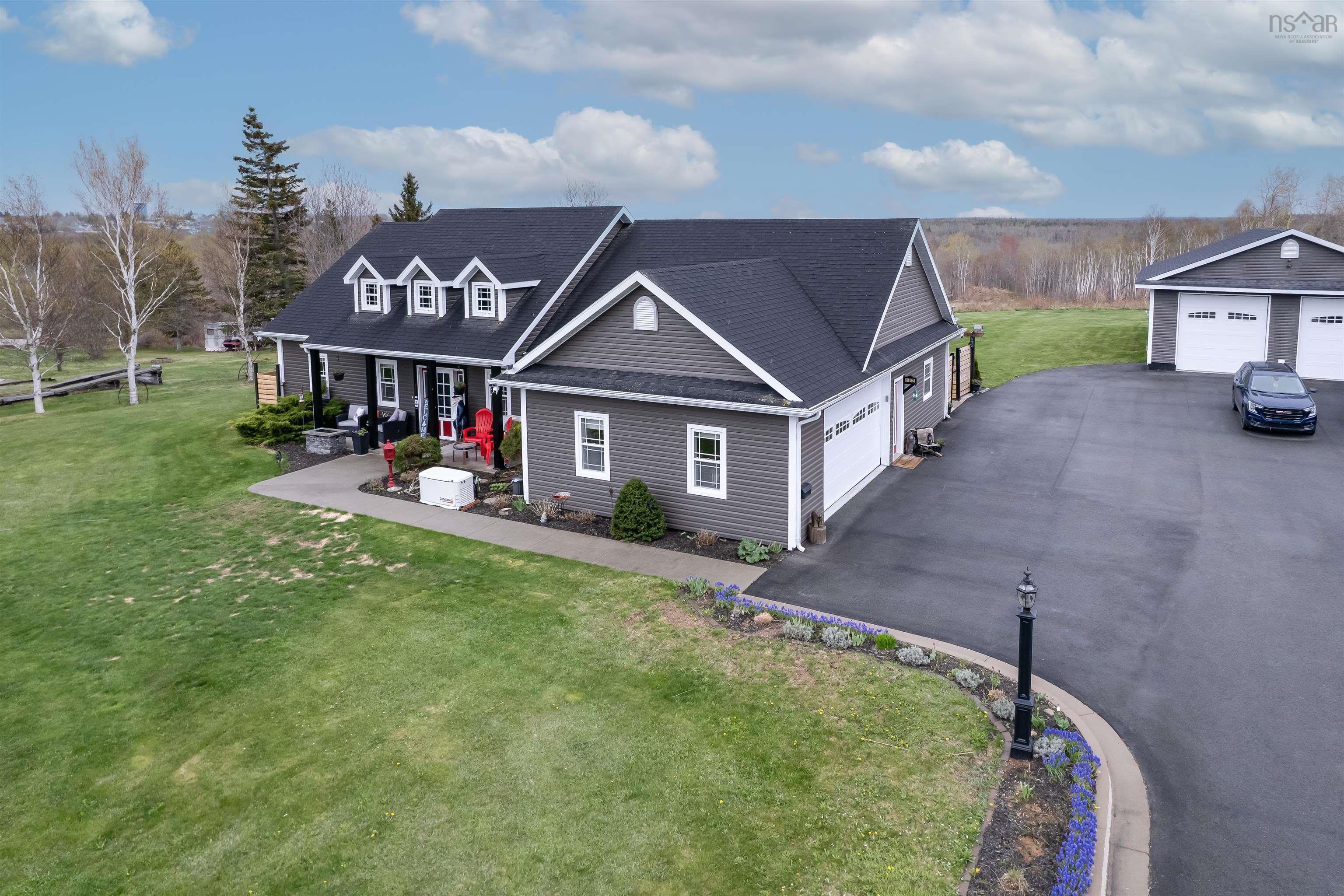 Expansive property featuring a grey siding main residence with a dark roof and three dormer windows