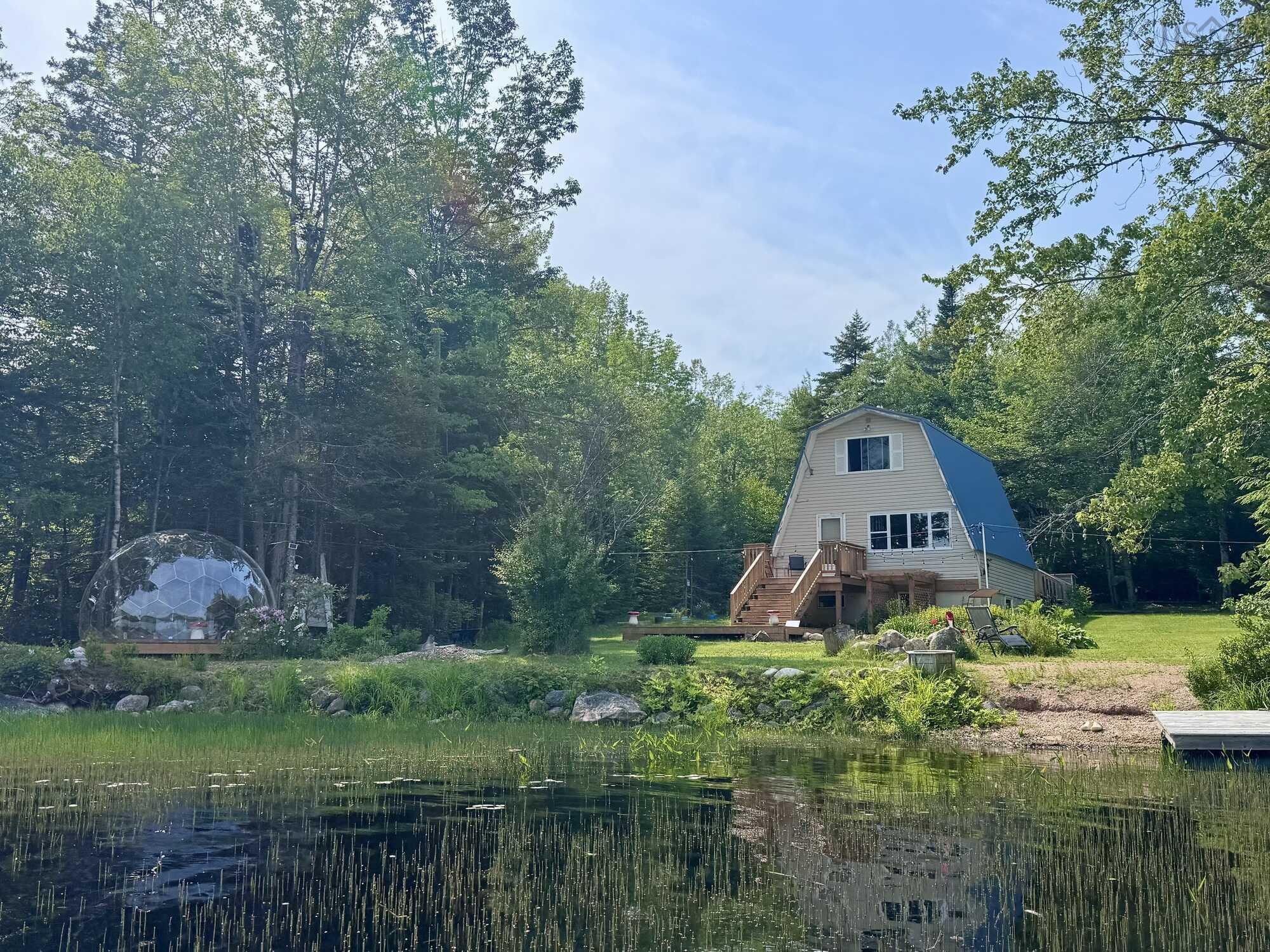 Waterfront A-frame style home featuring a blue metal roof and an expansive wood deck