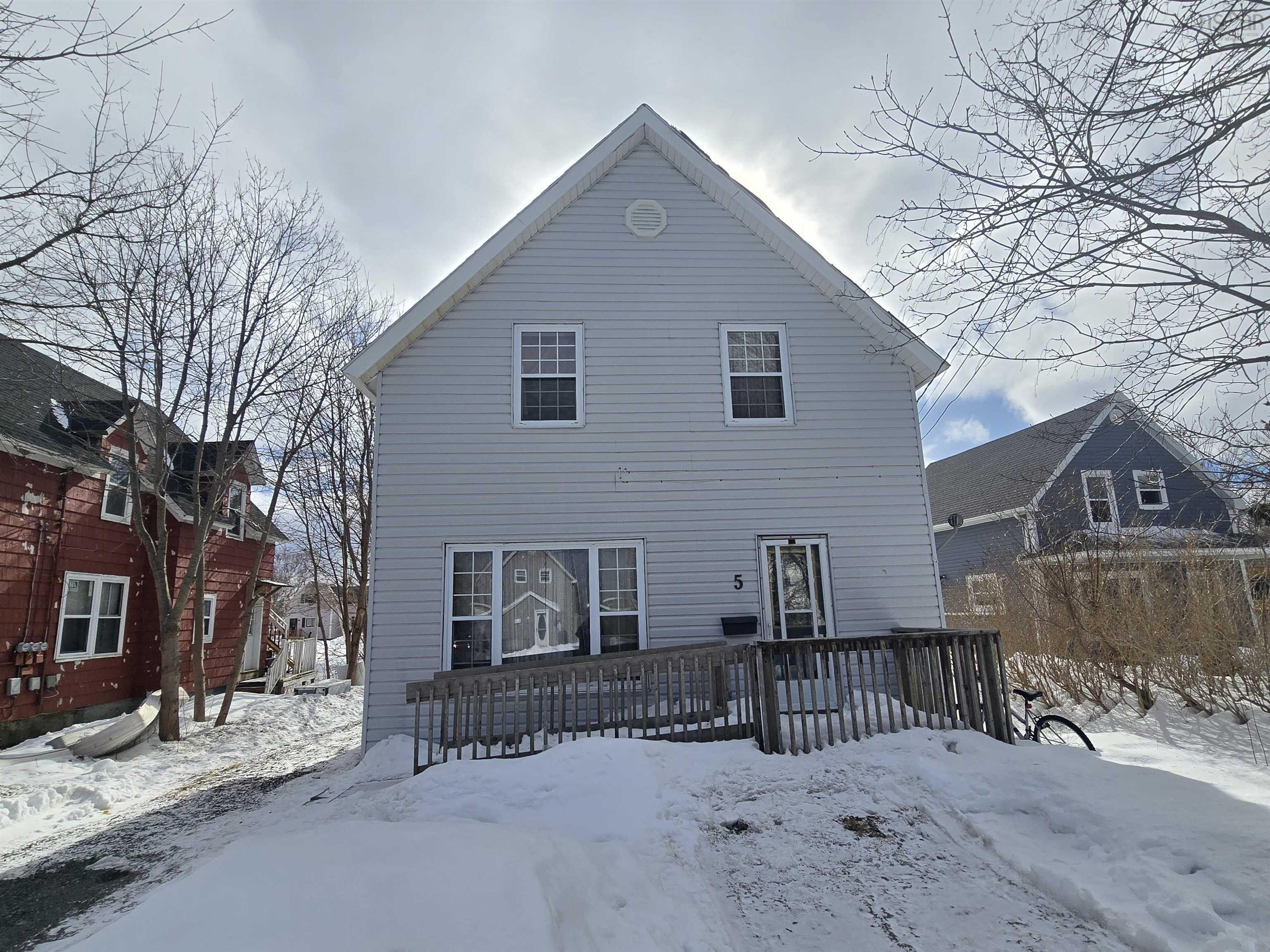 Snow covered back of property with a wooden deck