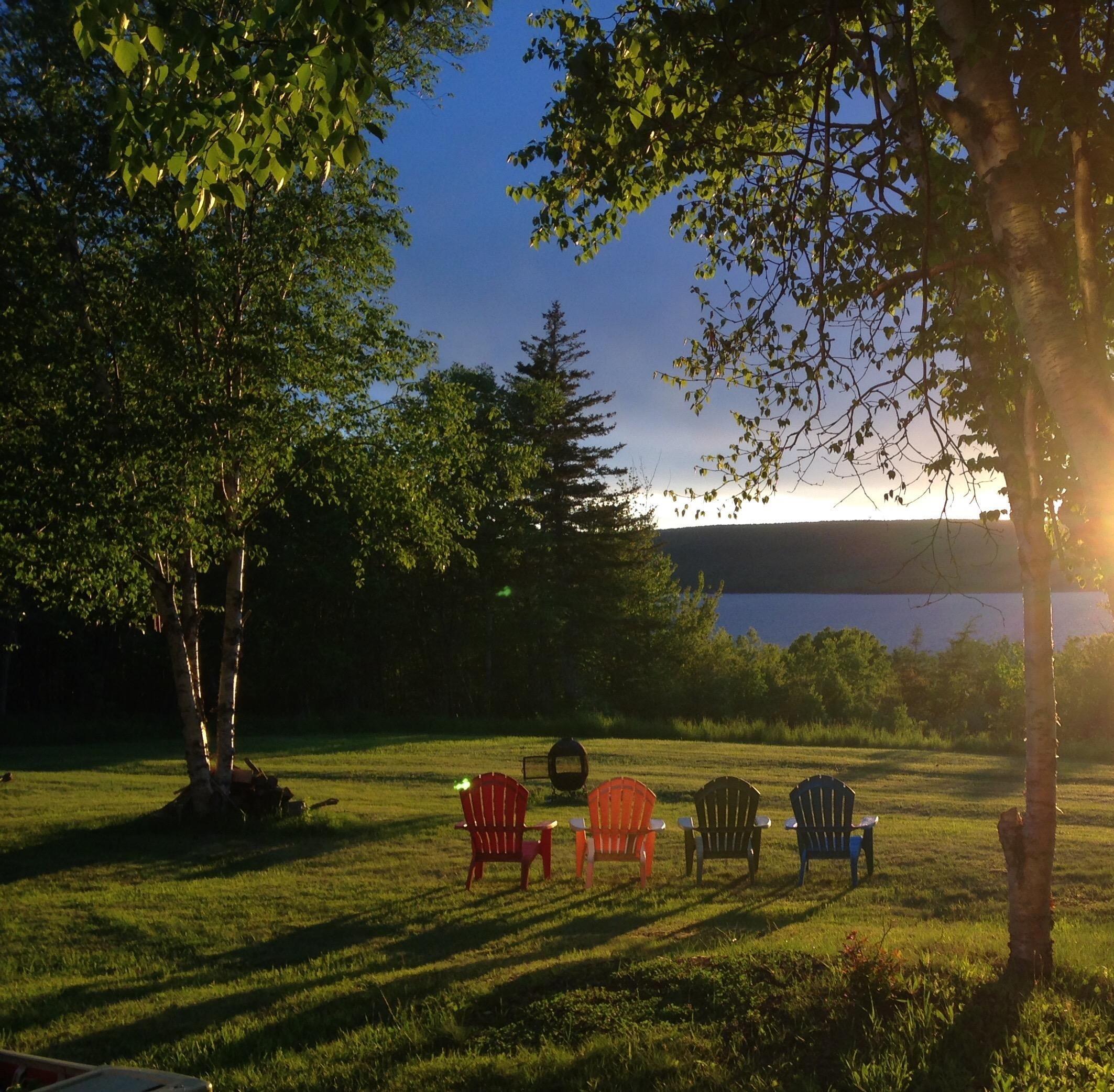 Expansive green lawn with mature trees and a distant body of water