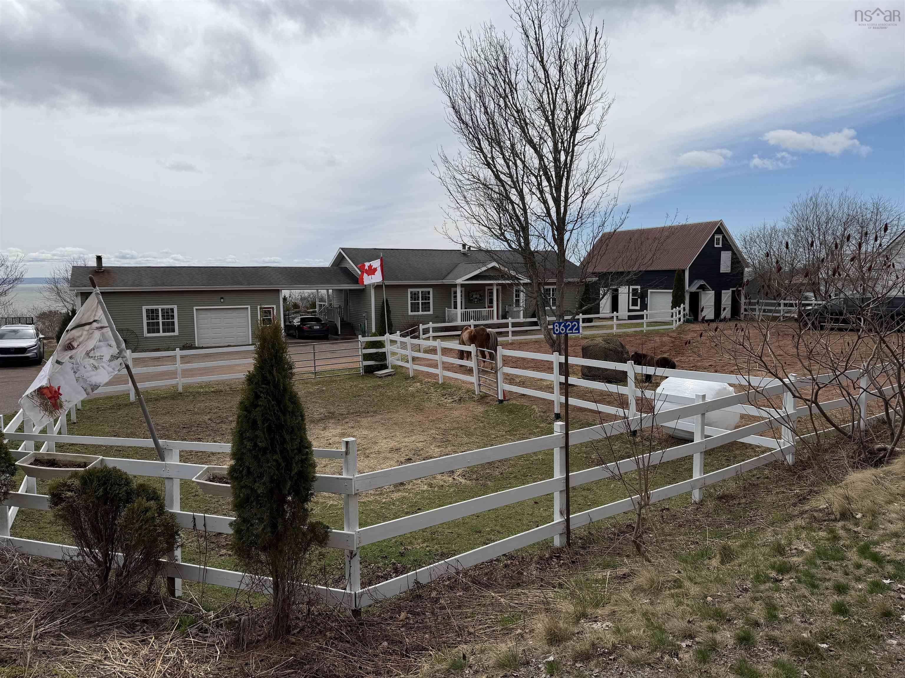 Multi-structure property featuring a main residence with attached garage, a separate barn-style building, and white perimeter fencing