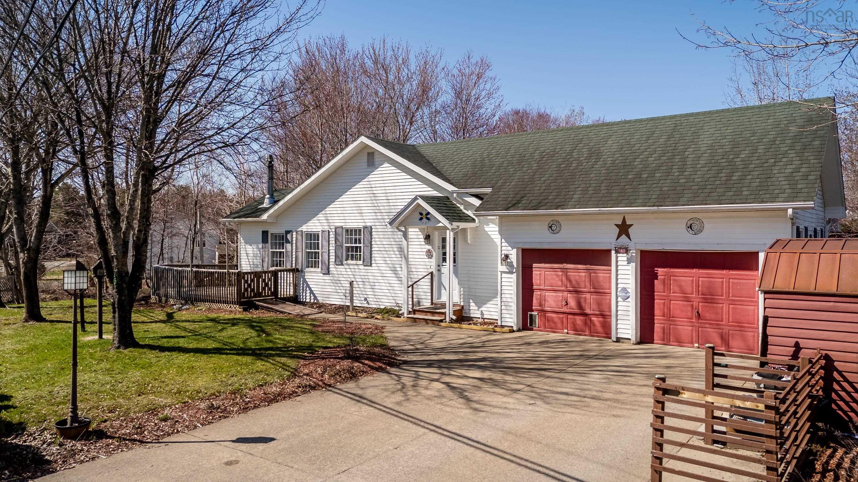 White siding residence featuring a two-car garage with red doors, a covered front entry, and a side deck with railing