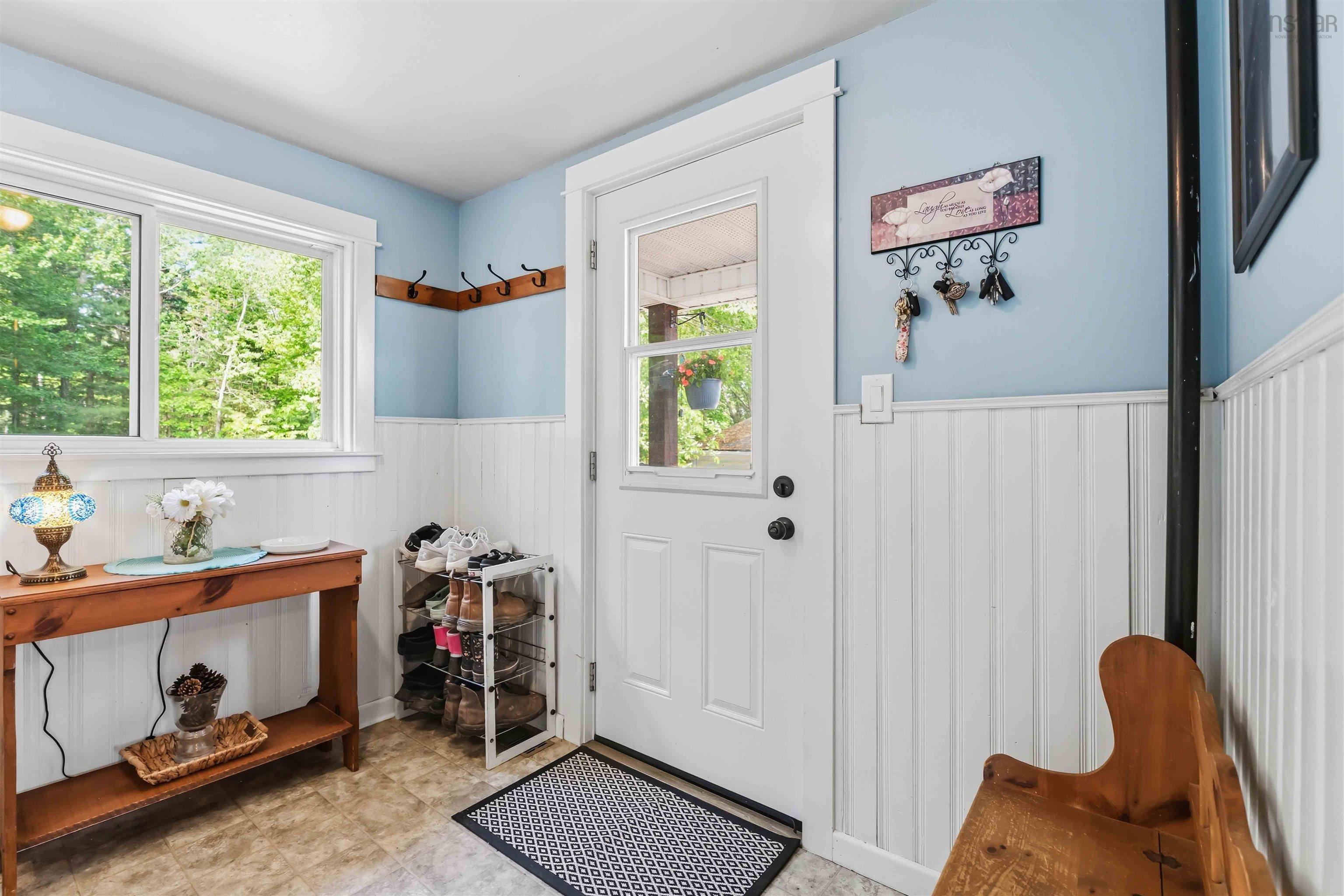 Entryway featuring a white paneled door with glass inserts, wood-finish flooring, and white wainscoting