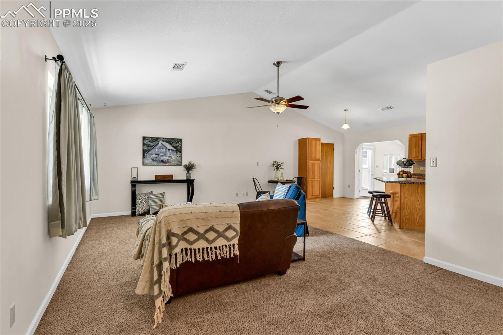 Bedroom with light carpet, baseboards, lofted ceiling, light tile patterned floors, and a ceiling fan