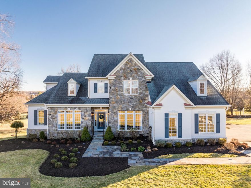 This one-of-a-kind, custom-built home offers the rare combination of expansive space, privacy, and versatility on a stunning 10-acre property in Leesburg. Tucked at the end of a tranquil cul-de-sac with no HOA restrictions, this property invites you to create your ideal lifestyle, whether you’re seeking serene country living, room for hobbies, or a place to entertain on a grand scale. Come inside to discover approximately 6,000 square feet of thoughtfully designed living space. The two-story foyer and family room immediately impress with soaring ceiling heights, a dramatic floor-to-ceiling stone fireplace, and a wall of windows and doors that seamlessly connect indoor and outdoor living. The heart of the home is the open-concept kitchen, featuring cathedral ceilings, a cozy brick-hearth fireplace, stainless steel appliances, granite countertops, and abundant cabinet storage. A sunlit dining area surrounded by windows and an island breakfast bar provide flexible dining and entertaining options. The true main-level primary suite is a highly desired feature, showcasing graceful tray ceilings, a private sitting area with serene views of the grounds, and a luxe en suite bath. Rich refinished hardwood floors flow through the common areas, and custom window treatments add a sophisticated touch. A remodeled home office provides a private workspace. Upstairs, three additional bedrooms provide generous space for family or guests. The walk-out basement includes a fifth legal bedroom, full bathroom, and flexible spaces for recreation or work. Outside, enjoy multiple large outdoor living areas that showcase the beauty of the property. A terraced deck offers sweeping views of landscaped grounds and mature trees, while the lower patio and flagstone side patio provide additional places to relax or entertain. The attached three-car garage is complemented by a detached barn/garage with space for up to five more vehicles or other uses, as well as an exterior storage shed. With over $500K in owner improvements, including updated roofing, gutters, and Hardie Plank siding, extensive landscaping and lighting, upgraded 119-gallon well water tank, expanded and recapped asphalt driveway, new garage doors and ProVia access doors, and a state-of-the-art water treatment system, this property highlights a rare pride of ownership. Enjoy the best of both worlds, with peaceful country charm and modern convenience, located just 10 minutes from downtown Leesburg and within easy reach of Dulles Airport and Washington D.C. Offering privacy, luxury, and endless possibilities, this is a very special property.