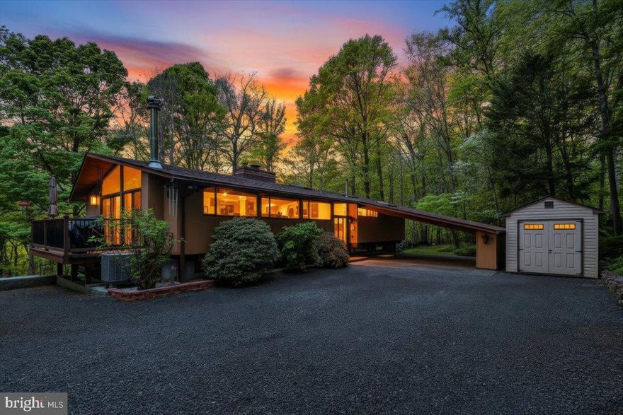 This exquisite Acorn Deck House with over 3200 sq. ft. of living space is nestled on 9.3 private acres overlooking the water views of Deer Creek. 1904 Nobles Mill showcases a rare opportunity to own a quality home designed by architects William Berkes and Robert Brownell. This mid-century modern home showcases post-and-beam architecture, vaulted cedar ceilings, wood floors, mahogany finishes and walls of windows which flood the home with natural light and frame breathtaking views. Enter through the traditional handcrafted waffle wood door to your 4 bdrm, 2 baths meticulously maintained home which offers multiple living spaces, including 2 family rooms with fireplaces featuring mantles crafted from walnut trees on the property. The open kitchen with an exposed brick wall, wet bar and wood stove also includes solid wood Rojahn cabinetry, Brazilian quartzite countertops, a triple pantry and high-end stainless-steel appliances. Outdoor living is unmatched with two decks, a private wet/dry sauna, hot tub and swim spa, all surrounded by peaceful nature. This is not just a home, it is a lifestyle! Additional features include: a hobby room with a built-in bed, custom cabinets and built-in bookcases and two sheds. Extensive updates have been complete. Most recent updates include a new HVAC system (2026), new carport parking pad (2026) and water softener (2023). This is a rare opportunity to own a nature retreat with high-end architecture.