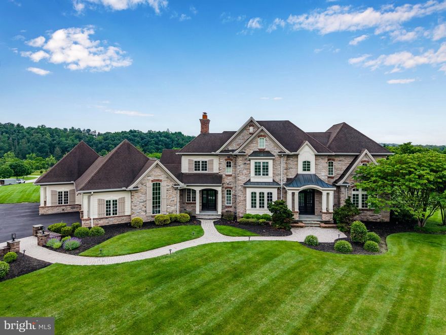 Experience resort-style living in this completely remodeled, custom-built Farinelli home, nestled on 5 private acres in the prestigious Estates of Allen Glen. With over 7,000 square feet of refined living space in the Mechanicsburg School District, every detail of this estate has been thoughtfully updated to perfection. A grand, tree-lined driveway welcomes you to the property, where you’ll take in stunning mountain views and impeccable landscaping. Enter through solid wood French doors into a soaring hardwood foyer, where a handcrafted staircase sets the tone for the architectural elegance found throughout. The two-story great room is a showstopper with floor-to-ceiling windows that flood the space with natural light and invite the outdoors in. The newly renovated gourmet kitchen is a chef’s dream—featuring quartz counters, custom cabinetry, seating for four at the oversized island, double ovens, butler’s pantry with second oven, gas fireplace, and a sunlit breakfast nook .Offering dual primary suites—one on each floor—both feature heated floors, custom cabinetry, spa-style baths, and expansive walk-in closets. Upstairs, three additional bedrooms include a private en-suite and a shared Jack & Jill bath. Two laundry rooms add convenience to everyday living. Thoughtful custom touches are everywhere: built-ins, coffered ceilings, triple crown molding, window seats, wainscoting, surround sound, and radiant heated floors. A spacious mudroom includes built-in dog bowls and four custom lockers. The fully finished walkout lower level offers a flexible layout for entertaining and wellness, including a large family room, gym with rubber flooring, craft room, playroom, and a full bath with direct access to the pool—ideal for summer living. Step outside to your private oasis: a custom-built Aquavisions saltwater pool with 50-foot sundeck, waterfall feature, self-cleaning system, and uplighting. Expansive paver patios and walkways lead to a covered outdoor living area with vaulted ceiling and wood-burning fireplace—perfect for year-round enjoyment. A 4-car garage completes this one-of-a-kind property. Every inch of this home has been elevated to deliver the finest in luxury, comfort, and quality craftsmanship. This is more than a home—it’s an experience. Schedule your private tour today.