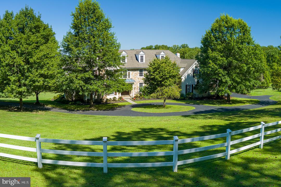 Welcome to 2 Spring Meadow Farm Lane — a spacious and elegant 5+ bedroom, 5+ bathroom home tucked away in a quiet Charlestown Township cul-de-sac. Set on 3.78 level, open acres in a small community of high-end homes, this property offers privacy, functionality, and exceptional living space inside and out. With over 6,000 square feet across the first two floors, the home features hardwood floors, generous room sizes, high ceilings, and large windows showcasing peaceful views. The main level includes a fireside living room, formal dining room, private office, sunroom (or second office), and a chef’s kitchen with granite countertops, stainless steel appliances, a center island, and a breakfast area — open to a spacious family room with a stone fireplace. Access the rear deck from several rooms, perfect for entertaining or relaxing outdoors. The first floor also includes two half baths and a practical mudroom. Upstairs, the primary suite consists of a sitting room, two walk-in closets, a tray ceiling, and a spa-style bathroom. Four additional bedrooms feature two en-suite bathrooms plus a Jack & Jill bath. The laundry room is conveniently located on this level, with stair access to an unfinished third floor for storage or future use.
The finished, walk-out lower level features a full bath, a bar area, an open recreation space, and additional finished rooms—ideal for a gym, a hobby area, or accommodating guests. Car enthusiasts will appreciate four garage bays: two attached and two in a detached garage with a walk-up loft space ready to be customized. The property is located in the award-winning Great Valley School District, offering easy access to the PA Turnpike, Paoli train station, shopping, and parks.