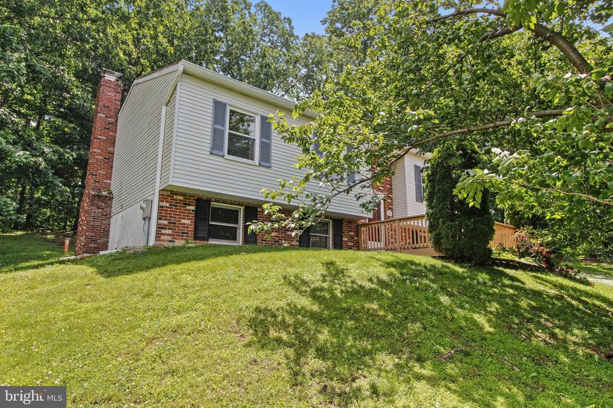 This Cozy Split Foyer has a Main Level that offers 3 Bedrooms, spacious Living Room, separate Dining Room, Kitchen, and recently updated Full Bathroom.  Sliding Doors off the Dining Room lead outside where you can sit back and relax tucked up to the hillside and surrounded by trees on the wonderfully secluded screened in deck with ceiling fan!  Living Room hosts built in shelves for those books, photos, and keepsakes, and cabinets for storage.  Other than the Kitchen and Bathroom Hardwood Floors are throughout the main level.  Downstairs features a large family room with wood burning Fireplace, quaint 4th Bedroom, Laundry, and spacious storage area/workshop.  Roof replaced in 2017, and well pump is 6 years young.   Great Location and good bones!