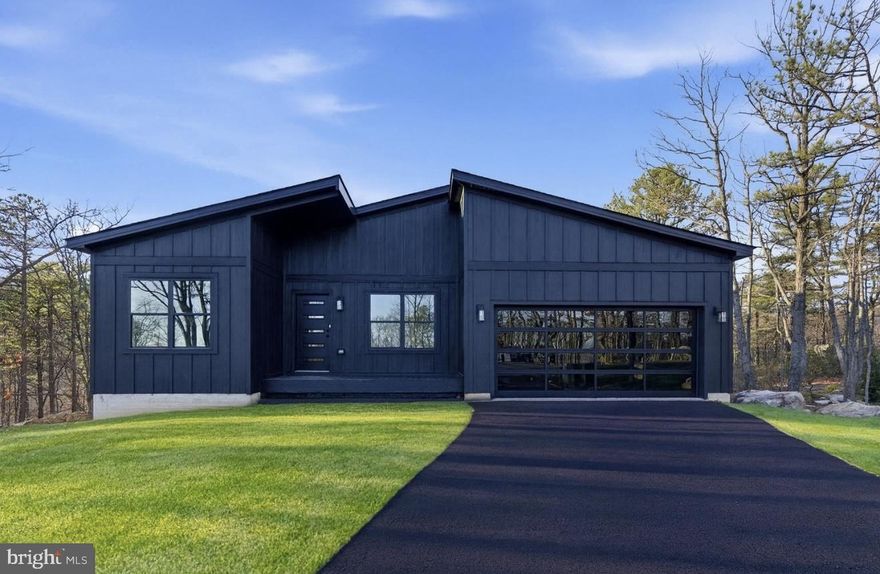 MOVE- IN READY!! This stunning new construction Mid-Century Modern home is nearly complete and located on a spacious 0.92 - acre lot in the desirable Woods Resort, offering beautiful mountain views . 
The Berkeley floorplan provides over 1,800 finished square feet on the main level, plus an additional 1,800 sq. ft. walkout basement with 9’ ceilings—perfect for future expansion or storage. The exterior showcases black siding for a bold, modern look. Inside features include luxury vinyl plank (LVP) flooring throughout, all-black interior doors with coordinating hardware, and a cozy living room fireplace framed by a black accent wall with wainscoting. The kitchen is equipped with white cabinets,  stainless steel appliance package, and a large center island ideal for entertaining. The spacious primary suite includes a bold black wainscoted accent wall and an en-suite bathroom featuring a barn door and  custom tile shower & modern finishes. Step outside to a 26’ x 10’ composite Trex deck with sleek cable railing, perfect for enjoying the peaceful natural setting. The home is eligible for Class A Woods Resort Membership, which offers amenities to indoor and outdoor pools, a spa, sauna, fitness center, golf courses, tennis courts, and more. Don’t miss the opportunity to own this stylish and thoughtfully designed home—