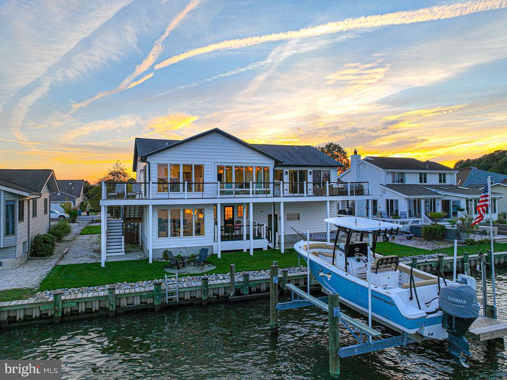 Located on the widest canal in Ocean Pines and offering expansive panoramas, direct open water access, and premier OC skyline views, this fully-furnished, turnkey property provides nearly 3,000 square feet of interior space, plus a screened-in porch, multiple decks, patio, dock and boat lift. Since 2020, the entire property - inside & out - has been completely renovated, redesigned and reconfigured down to the studs with the most discerning eye and attention to detail. From landscaping to decking, from siding to major systems to boat lift, from kitchen, baths, and flooring to plumbing, electrical and waterproofing, no expense was spared in this full renovation.
Enjoy the sunrise over Ocean City from the rear deck, screened-in porch, kitchen or upper level family room. An extension of the upper level family room, the rear deck has been expanded and runs the entire length of the home, with composite decking and cable railings so you can enjoy an unobstructed view.
Interior upgrades include - upper level reconfigured to maximize water views, full kitchen renovation with Green Forest cabinetry, quartz counters, GE Profile appliances, additional beverage fridge, and expanded pantry, all bathrooms fully renovated, new LVP flooring throughout the main living spaces and primary bed & bath, and new carpeting installed in three bedrooms and on stairs, recessed lighting added, new lighting fixtures installed throughout, and all wiring updated, custom window treatments installed throughout, including heat-blocking, black out roller shades and blinds.
Exterior upgrades include - replaced dock stringers and decking, installed a 12.5k lb boat lift with remote, and 4 new pilings installed for lift, full replacement of siding/gutters/porch posts/soffits, 8” plank siding with black shutters, soffits, and gutters, two new exterior doors in back of house, yard sodded, large rocks and stone patio added, paved driveway (previously gravel), updated front landscaping including new irrigation system, new drain on driveway, and two new exterior faucets, replaced and extended both back decks and front porch renovation, all decking replaced with composite, installed irrigation system for grass, updated external lights and post light, replaced glass in front door and side windows, replacement of all screen doors and screens in back porch.
Major system updates - Crawl space fully encapsulated and waterproofed, two new HVAC systems installed per FEMA standards, one natural gas and one electric, two new thermostats (Ecobee), an EV charger and new electric panel installed, Ring security system and external cameras installed, solar dock lighting and flag pole with solar light.
Enjoy all the amenities of Ocean Pines: an oceanfront beach club with parking on 50th street in Ocean City, a public Yacht Club in Ocean Pines, five pools, two marinas, a premier racquet sports complex, and a Robert Trent Jones Sr.-designed championship golf course.