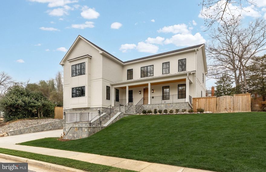 Tucked away on a quiet cul de sac in coveted Country Club Hills, 4283 38th Street North offers a rare blend of seclusion, sophistication, and striking design. Elevated above the street and framed by manicured landscaping, this custom residence was built in 2023 by CR Custom Homes and showcases where East Coast tradition meets West Coast style.

The exterior merges the charm of a modernized Colonial with warm farmhouse influences. Interiors, curated by Santa Monica designer Tracy Gilmore, embrace a refined Southern California aesthetic. A broad stone staircase framed by tiered retaining walls leads to a welcoming front porch, setting the stage for elegance inside.

A dramatic foyer, filled with natural light, spans the main level and highlights exceptional craftsmanship: wide plank white oak floors in herringbone, ten foot ceilings, eight foot quadruple hinged doors, Phillip Jeffries wallpaper, and motorized window treatments.

Off the entry, a private study balances a main level bedroom suite ideal for guests or multigenerational living. The formal dining room, introduced by a refined vestibule, features a large bay window and connects via a butler’s pantry to the kitchen.

At the center of the home, the kitchen is both showpiece and gathering space. Carrara marble wraps perimeter counters and backsplash, while a black leathered marble island adds contrast. Stacked inset cabinetry conceals appliances for a clean, modern look. An adjacent dining area and spacious family room flow seamlessly, with reclaimed wood beams, a linear fireplace, and arched built ins enhancing the atmosphere.

The primary suite occupies its own upper level wing. A vestibule introduces the serene bedroom, while a second leads to a boutique style dressing room with custom shelving. The spa inspired bath includes radiant heated floors, a walk in shower room, double vanity, and separate water closet.

At the top of the stairs, a loft creates a cozy reading nook and connects to three additional ensuite bedrooms with custom walk ins. A bold laundry room with patterned tile completes the level. The lower level includes a fifth bedroom suite, a large recreation room, and a mudroom accessing the two car garage.

The backyard is fully fenced and landscaped, with open lawn, hardscape, and mature greenery. A covered rear porch with retractable screens provides seamless indoor outdoor living for year round dining and relaxation.

Modern systems elevate efficiency and comfort, including impact rated windows and doors, backup generator, tankless water heater, integrated Sonos, comprehensive security, and extensive drainage infrastructure.

Located just a mile from Chain Bridge and moments from Glebe Road Park, the home offers easy access to city amenities and natural beauty alike.

4283 38th Street North is more than a home. It is a masterclass in design, comfort, and function. Every finish has been thoughtfully selected. This is luxury living at its finest.