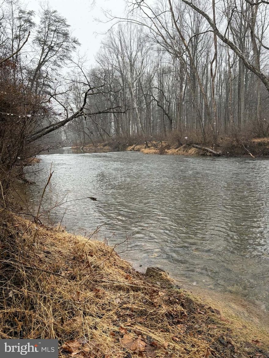 Enjoy 4.0 acres of waterfront property along the North River, located in Hampshire County, approximately 2.5 hours from Washington, DC. Set outside the flood plain, this property offers direct river access without the requirement for flood insurance, combining peace of mind with the beauty of true riverfront living.
The home is best described as a rustic cabin-style retreat, featuring a spacious open loft sleeping area and one full bath. Unique custom woodwork throughout reflects the artistry of a previous owner and adds warmth and character to the interior. It has electric heat and a wood stove, and an enclosed hot tub area offers year-round relaxation.
A three-bay detached garage and multiple outbuildings provide ample space for vehicles, workshop needs, and storage of outdoor or recreational equipment.
With wooded acreage, river frontage, and a setting that feels private yet accessible, this property presents an excellent opportunity for a weekend getaway, recreational base, or full-time mountain retreat.  This property is being sold as-is and requires cash or conventional loan.