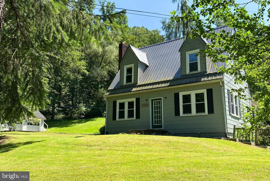 Discover this charming Cape Cod home nestled just steps from a serene creek, offering peaceful country living. Sitting on almost 2 acres, this three-bedroom, one-bath includes a spacious two-car garage with a finished room above—perfect for a home office, studio, or guest space.  The inviting interior features gleaming hardwood floors throughout, with warm cherry wood accents in the living and dining rooms. Relax by the cozy wood-burning fireplace or entertain in the bright, updated kitchen adorned with white cabinets, butcher block countertops, and recessed lighting. The spacious bedrooms and updated bathroom provide comfort and convenience.  Outside, enjoy the tranquility of your private slice of nature, complete with an outbuilding ideal for chickens or gardening needs. Whether you're seeking a quiet retreat or a place to call home, this property has it all.  Don’t miss out on this unique opportunity! Call today to schedule a tour and experience all this delightful home has to offer!