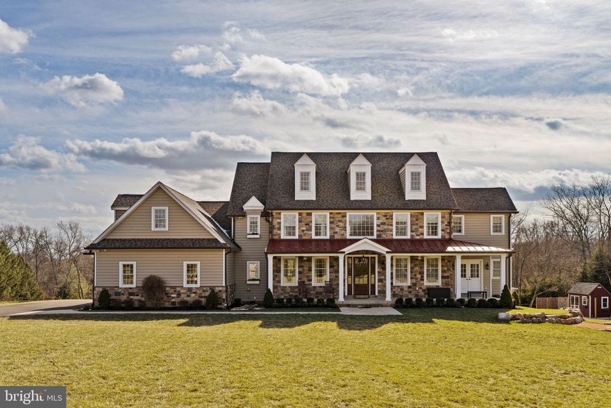 Welcome to a home where elegance and craftsmanship come together, set on a breathtaking 3-acre property in one of Newtown's most sought-after locations. This 4-bedroom, 4.5-bathroom home spans over 5,000 square feet, offering a masterful blend of luxury, comfort, and modern convenience. As you arrive, a long private driveway winds its way to the front of the home, revealing an architectural masterpiece. The exterior showcases timeless natural stone accents and an inviting porch with a standing seam metal roof—perfect for taking in the serene views of the surrounding landscape. Enter through the stately solid mahogany front door into the grand two-story foyer, where wide-plank oak flooring and a graceful Juliet balcony set the tone for this extraordinary residence. The thoughtfully designed floor plan seamlessly balances sophisticated entertaining spaces with the comfort of everyday living. The heart of the home is the stunning great room, highlighted by reclaimed barn wood beams, a natural stone gas fireplace with a hand-hewn wood mantel, and oversized windows that bathe the space in natural light. Adjacent is the formal dining room, featuring elegant coffered ceilings and cottage-style windows that create a warm, inviting ambiance. For the culinary enthusiast, the chef’s kitchen is nothing short of spectacular. It boasts custom Starmark cabinetry, expansive granite countertops, and professional-grade appliances, including a dual-fuel range, vent hood, warming drawer, and not one but three SubZero refrigerators. The oversized farmhouse sink and fully equipped prep pantry elevate this space to a true culinary haven. Nearby, the butler’s pantry offers added convenience with an ice maker, instant hot/cold water dispenser, and a charming Nantucket sink. Practicality meets style in the mudroom, where custom-built storage cubbies, a pet shower, and a secondary laundry area make day-to-day living effortless. For remote work or quiet study, the private office with sliding barn doors offers the perfect sanctuary. Upstairs, each of the four spacious bedrooms is designed with both comfort and style in mind. Three full bathrooms on this level feature luxurious finishes, while the media room—complete with a 100” screen and state-of-the-art surround sound—provides the ultimate entertainment experience. A second laundry room, equipped with dual hookups, soundproof drywall, and a waterproof floor system, adds unparalleled convenience. The lower level offers endless possibilities, with its own private entrance and a finished full bathroom, making it ideal for a home office, gym, or future in-law suite. The third level, already framed and floored, is a blank slate ready for customization. Car enthusiasts will appreciate the oversized 4-car garage, featuring insulated doors and a durable polyaspartic epoxy floor. The home is equipped with a Kohler liquid-cooled whole-house generator, ensuring peace of mind in any weather. Outside enjoy the professionally designed backyard oasis. A custom fire pit with natural stone boulders and a bluestone deck creates the perfect setting for outdoor gatherings. The expansive yard provides a peaceful escape, surrounded by lush greenery and endless opportunities for recreation or relaxation. This exceptional property offers a rare combination of luxurious amenities, unparalleled craftsmanship, and natural beauty—all in the heart of Newtown. Don’t miss the chance to make this one-of-a-kind home your private sanctuary.