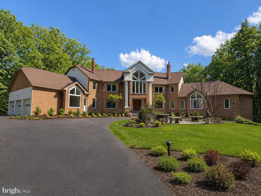 Designed as the builder’s personal residence, this home was conceived on a scale and level of privacy that is increasingly difficult to replicate. Set on 2.5 secluded acres, and offering more than 16,000 square feet of finished living space, it carries true estate presence. The residence includes 6 bedrooms, 7 full baths, and 3 half baths, thoughtfully designed to balance grandeur with livability. Owners enjoy convenient access through Avenel without being subject to Avenel HOA fees; a meaningful and rare advantage in this location.
A long private driveway sets the tone, opening to a circular drive that creates a gracious sense of arrival and leads to the four-car side-entry garage and expansive motor court.
Recent capital improvements include brand new Andersen windows, a recently updated roof, and mechanical upgrades. Expansive picture windows throughout the home frame the surrounding greenery and pull natural light deep into the living spaces. The result is a bright, open feel that balances the home’s impressive scale. The kitchen has been renovated with quartz countertops, quality appliances, and generous storage. While certain finishes present an opportunity for aesthetic modernization, the home’s proportions and construction provide an exceptional foundation for thoughtful refinement.
The outdoor amenities elevate the property into a true private compound. Multiple terraces and patios overlook the grounds, complemented by a full outdoor tennis and basketball court, an indoor athletic court, and a climate-controlled indoor pool with a retractable roof for year-round enjoyment.
Inside, scale and architectural presence define the interiors. A dramatic two-story foyer opens to formal living and dining rooms, each anchored by a fireplace. The family room, centered around a striking stone fireplace and surrounded by walls of glass, connects seamlessly to the outdoor entertaining spaces. Five fireplaces throughout the home add warmth and depth.
One of the property’s most distinctive features is the expansive main-level primary suite. With a cathedral ceiling, generous sitting area with fireplace, two oversized walk-in closets, and its own dedicated private gym, this suite functions as a true retreat. The newly renovated primary bath is magazine-worthy, thoughtfully designed with refined spa-like presence that elevates the entire suite.
Upstairs, two separate primary bedroom suites each include dedicated sitting rooms and spacious baths, providing exceptional privacy and comfort. One of the secondary bedroom suites features its own steam shower and free-standing tub, adding another layer of luxury. In fact, every bedroom in the home is designed as a true suite, each with its own private bathroom and a large walk-in closet, ensuring comfort, independence, and thoughtful separation throughout.
From the walkout lower level, doors open directly to the climate-controlled indoor pool, allowing effortless access between recreation and relaxation while maintaining privacy and year-round enjoyment. It continues the lifestyle focus with a substantial recreation lounge, a full secondary kitchen for entertaining, a wet bar, a media room, a fitness space, an indoor sports court, and extensive storage. A large spa-like bath with a steam shower serves this level, enhancing the home’s wellness appeal and complementing the indoor athletic amenities.
From its exquisite indoor spaces to its resort-like outdoor amenities, this Bethesda estate offers an unparalleled lifestyle in proximity to the area’s revered dining, retail, and entertainment. This residence is ideal for multi-generational living or to accommodate live-in staff.  Zoned for Carderock Springs ES, Thomas W. Pyle MS, and Walt Whitman HS.