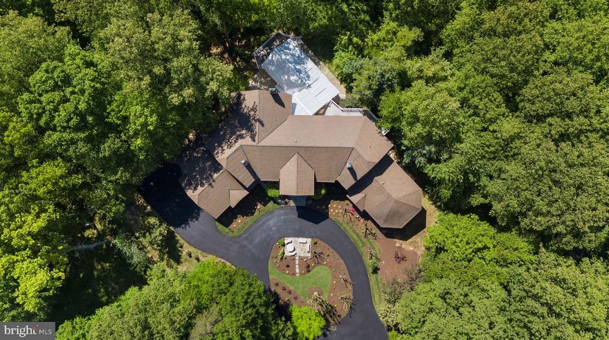 Designed as the builder’s personal residence, this home was conceived on a scale and level of privacy that is increasingly difficult to replicate. Set on 2.5 secluded acres, and offering more than 16,000 square feet of finished living space, it carries true estate presence. The residence includes 6 bedrooms, 7 full baths, and 3 half baths, thoughtfully designed to balance grandeur with livability. Owners enjoy convenient access through Avenel without being subject to Avenel HOA fees; a meaningful and rare advantage in this location.
A long private driveway sets the tone, opening to a circular drive that creates a gracious sense of arrival and leads to the four-car side-entry garage and expansive motor court.
Recent capital improvements include brand new Andersen windows, a recently updated roof, and mechanical upgrades. Expansive picture windows throughout the home frame the surrounding greenery and pull natural light deep into the living spaces. The result is a bright, open feel that balances the home’s impressive scale. The kitchen has been renovated with quartz countertops, quality appliances, and generous storage. While certain finishes present an opportunity for aesthetic modernization, the home’s proportions and construction provide an exceptional foundation for thoughtful refinement.
The outdoor amenities elevate the property into a true private compound. Multiple terraces and patios overlook the grounds, complemented by a full outdoor tennis and basketball court, an indoor athletic court, and a climate-controlled indoor pool with a retractable roof for year-round enjoyment.
Inside, scale and architectural presence define the interiors. A dramatic two-story foyer opens to formal living and dining rooms, each anchored by a fireplace. The family room, centered around a striking stone fireplace and surrounded by walls of glass, connects seamlessly to the outdoor entertaining spaces. Five fireplaces throughout the home add warmth and depth.
One of the property’s most distinctive features is the expansive main-level primary suite. With a cathedral ceiling, generous sitting area with fireplace, two oversized walk-in closets, and its own dedicated private gym, this suite functions as a true retreat. The newly renovated primary bath is magazine-worthy, thoughtfully designed with refined spa-like presence that elevates the entire suite.
Upstairs, two separate primary bedroom suites each include dedicated sitting rooms and spacious baths, providing exceptional privacy and comfort. One of the secondary bedroom suites features its own steam shower and free-standing tub, adding another layer of luxury. In fact, every bedroom in the home is designed as a true suite, each with its own private bathroom and a large walk-in closet, ensuring comfort, independence, and thoughtful separation throughout.
From the walkout lower level, doors open directly to the climate-controlled indoor pool, allowing effortless access between recreation and relaxation while maintaining privacy and year-round enjoyment. It continues the lifestyle focus with a substantial recreation lounge, a full secondary kitchen for entertaining, a wet bar, a media room, a fitness space, an indoor sports court, and extensive storage. A large spa-like bath with a steam shower serves this level, enhancing the home’s wellness appeal and complementing the indoor athletic amenities.
From its exquisite indoor spaces to its resort-like outdoor amenities, this Bethesda estate offers an unparalleled lifestyle in proximity to the area’s revered dining, retail, and entertainment. This residence is ideal for multi-generational living or to accommodate live-in staff.  Zoned for Carderock Springs ES, Thomas W. Pyle MS, and Walt Whitman HS.