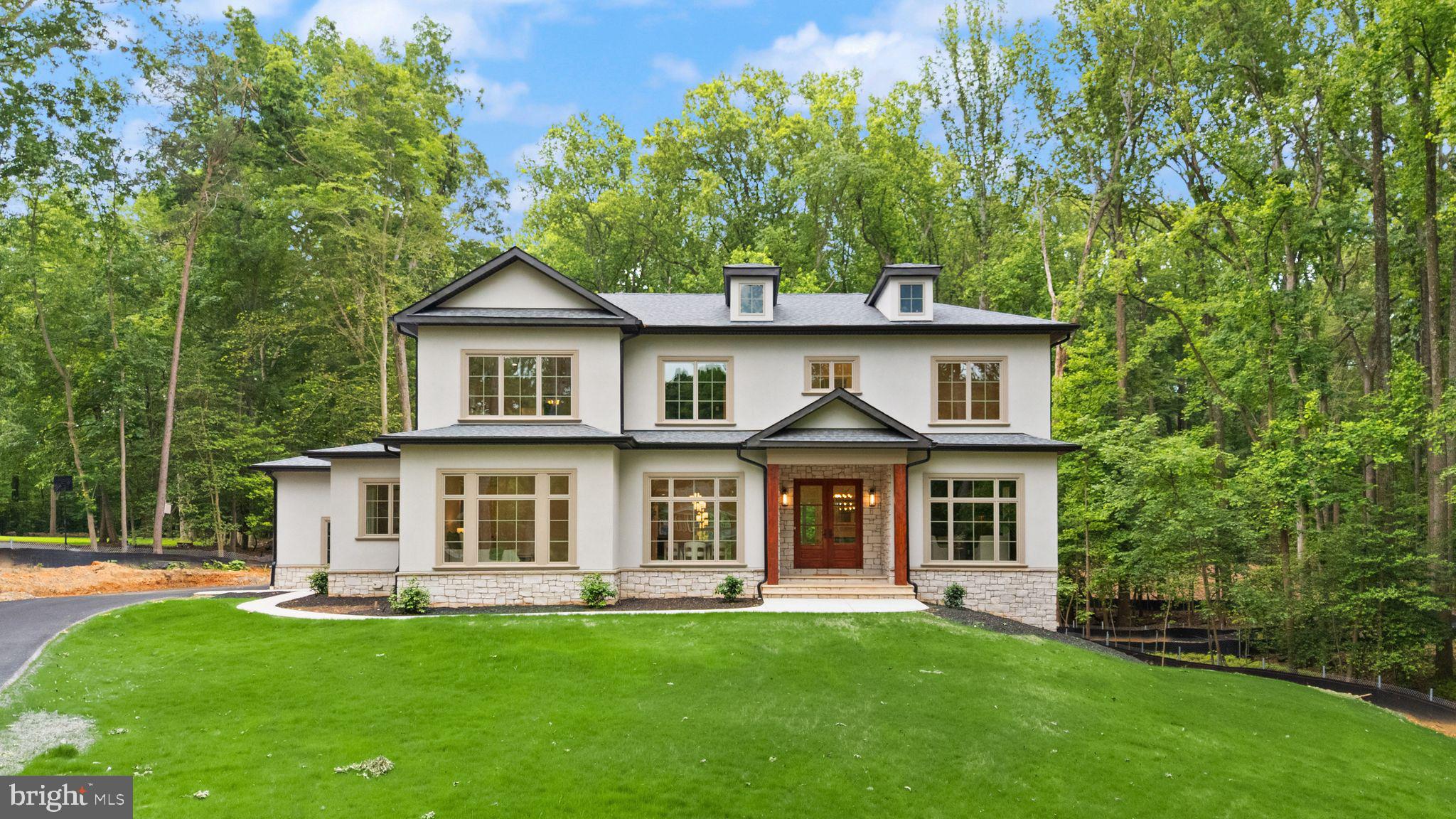 Everyday living is elevated in this custom new construction home by award-winning Faber Custom Builders, perfectly situated on nearly 2 private wooded acres in a prestigious estate neighborhood. This one-of-a-kind residence blends timeless design with curated luxury.
The elegant stucco exterior is paired with Pella Lifestyle windows in a deep fossil hue and a solid mahogany front door, setting the tone for high-end finishes throughout. Inside, the expansive open-concept layout centers around a chef’s kitchen with custom cabinetry, designer fixtures, professional-grade appliances, and a hidden scullery-style pantry with beverage station.
A see-through fireplace connects the great room to a covered rear porch, perfect for three-season enjoyment. A modern mudroom, dedicated guest entry, and main-level guest suite offer thoughtful functionality.
Upstairs, a gallery landing leads to spacious bedroom suites, each with spa-inspired en-suite baths and walk-in closets. The primary suite features a black marble accent wall, natural light, and elevated finishes. The laundry room is both stylish and functional.
The finished lower level includes a large rec room, bedroom with en-suite bath, and flexible unfinished space for a gym, theater, wine cellar, or golf simulator.
This peaceful setting offers serene, private living with exceptional convenience. Just 10 minutes to Great Falls Village Centre and with easy access to Route 7, the Dulles Corridor, and Tysons you're perfectly positioned for work, school, and weekend escapes. Top-rated Fairfax County schools, nearby Seneca Regional Park, and the natural splendour of Great Falls National Park. A home where space, serenity, and setting harmonize.