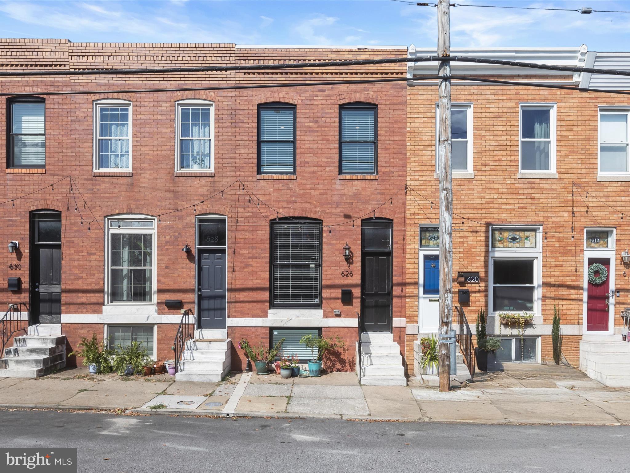 Charming Renovation in the Heart of Brewers Hill! Experience the best of city living in this stunning Building Character renovation, complete with 7 years remaining on the CHAP tax credit, a rare opportunity for long-term savings. Perfectly positioned just steps from vibrant shopping, dining, and entertainment, this stylish brick rowhome blends historic charm with modern luxury across three thoughtfully finished levels. Inside, you’re welcomed by soaring ceilings, exposed brick accents, crown molding, and gleaming hardwood floors that set a sophisticated tone. The spacious living room flows seamlessly into the dining area, featuring custom-built-in shelving that is perfect for displaying or housing audio equipment. At the heart of the home, the chef’s kitchen showcases a striking waterfall quartz island with seating, 42” soft-close cabinetry, subway tile backsplash, quartz counters, and premium stainless steel appliances, offering both function and style for daily living and entertaining. Upstairs, the luxurious primary suite boasts a walk-in closet, recessed lighting, hardwood flooring, and a spa-like en-suite bath with dual vanities and a glass-enclosed shower with dual shower heads. A secondary bedroom features vaulted ceilings, a brick accent wall, and easy access to a designer hall bath with a rain shower. A conveniently placed laundry closet completes this level. From here, step up to the private rooftop Trex deck with breathtaking panoramic city views, ideal for hosting guests or unwinding under the skyline. The fully finished lower level provides incredible versatility with a third bedroom, full bath, private office, or optional fourth bedroom, plus valuable storage space. Additional upgrades include a whole-house audio system for the ultimate modern lifestyle. Outside, enjoy the convenience of a private parking pad, a true luxury in city living. With unmatched craftsmanship, high-end finishes, and an unbeatable Brewers Hill location near I-95, I-895, and I-83, this home is a rare gem that won’t last long.