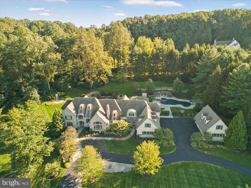 A gateway to luxurious living, Jalousie Pines offers an enviable locale, high-end diverse amenities and systems, and the sought after security and privacy today’s celebrity and Class A executive clientele
demand.  An incomparable masterpiece, this splendid property with a fully renovated and expanded
interior and an exterior including newly constructed custom entertaining pavilion by Worthington & Shagen Builders and a custom free form pool with sun shelf, elevated circular spa, and multiple waterfall
features designed by Aqua Bello Pools, is immersed in the elite Bucks County countryside. Accessible via
a meandering drive, owners will appreciate the 7-car gated garages and auto court area. With three
levels of finished living space, this exclusive 6 bedroom/7 full & 2 half bath 10,000+SF, 13-acre French Country estate originally crafted by Richard Zaveta is a fusion of luxury retreat and the tranquility of nature. The main level features an expansive double island gourmet kitchen that champions elegant design, top quality materials, Sub-Zero & Wolf appliances with practicality and high-performance finishes, an accompanying scullery/butler’s pantry, laundry, sunroom, home office with fireplace and built-in AV
for television, an inviting formal dining room, living room and a spacious great room with dramatic
fireplace (one of 5 in the main house in addition to 2 exterior fireplaces) —the entirety of the main level
is bathed in natural light and showcases panoramic views of lush greenery, majestic acreage, the grand
covered outdoor kitchen and living areas, a sparkling free form pool with dramatic aquatic design & custom features, and inviting lounge spaces all melding into a haven for relaxation. The main level is
complete with private au pair/in-law’s quarters with separate outdoor entrance, attached 4-car garage.  In addition to the attached 4-car garage, there is a detached 3-car garage w/ full bath  (Note: this full bath is counted as the 7th full main level bath) for pool guests & a large upper-level unfinished room perfect for conversion to gym, office, or additional storage. The main house upper level is accessible via the grand main staircase, the back staircase, and the elevator that services all levels of the home. The Primary Suite is exceptional with decadent amenities including a sitting room with fireplace, an enviable custom walk-in wardrobe, an inspired snuggery independent of the main sleeping quarters, and a large bathroom with radiant heat floors.  An additional “suite” bedroom with sitting area, fireplace, radiant heat bathroom floors, and a custom closet, and 2 additional large bedrooms with full bathrooms round out the upper level. One of the many highlights of the lower walkout level is the expansive 1,000+ bottle wine cellar, fully insulated and temperature controlled, a full bedroom and bath, game area, large TV entertainment area, and a large personal gym that could be converted into a large theater room. The magnificence of the home's interior is further elevated by the overwhelming grandeur and elegance of the very private backyard oasis.  The custom designed pavilion is easily accessible from the main house sunroom. The pavilion includes an extra-large Alfresco grill, two range top burners, two refrigerators, an island bar with sink, a large dining table area, and an expansive seating area to watch one of the two televisions and fully appreciate the stunning outdoor fireplace.  In addition to the warmth of the fireplace, thermal heaters in the roofed area provide for extended outdoor entertaining and year-round comfort.  During the Summer months family and friends will enjoy the large free form pool with sun shelf and depths ranging from 3' to 8', an elevated circular spa with overflow waterfall into the main pool, separate elevated seating area near the spa, a full custom concrete pool deck with diving rock, 3 pool waterfall features, and 3 dramatic fire bowls.