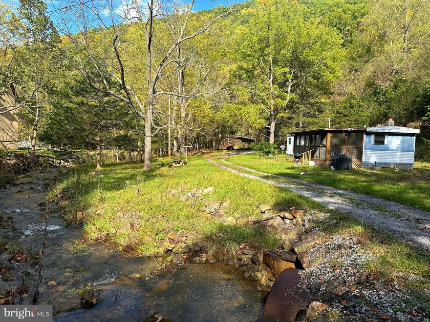 Watch the STREAM flow by from your front porch.  Rehab the current small mobile home  or build your tiny cabin to listen to the babbling creek.  Unrestricted acreage make this the perfect getaway property.    All season, easy access off a paved county maintained road.  Property is improved with public water and electric, detached carport & outbuildings.   Property is being sold "AS IS".    Don't miss this little gem, just minutes from the small town of Franklin.   Call today for a showing of this property.