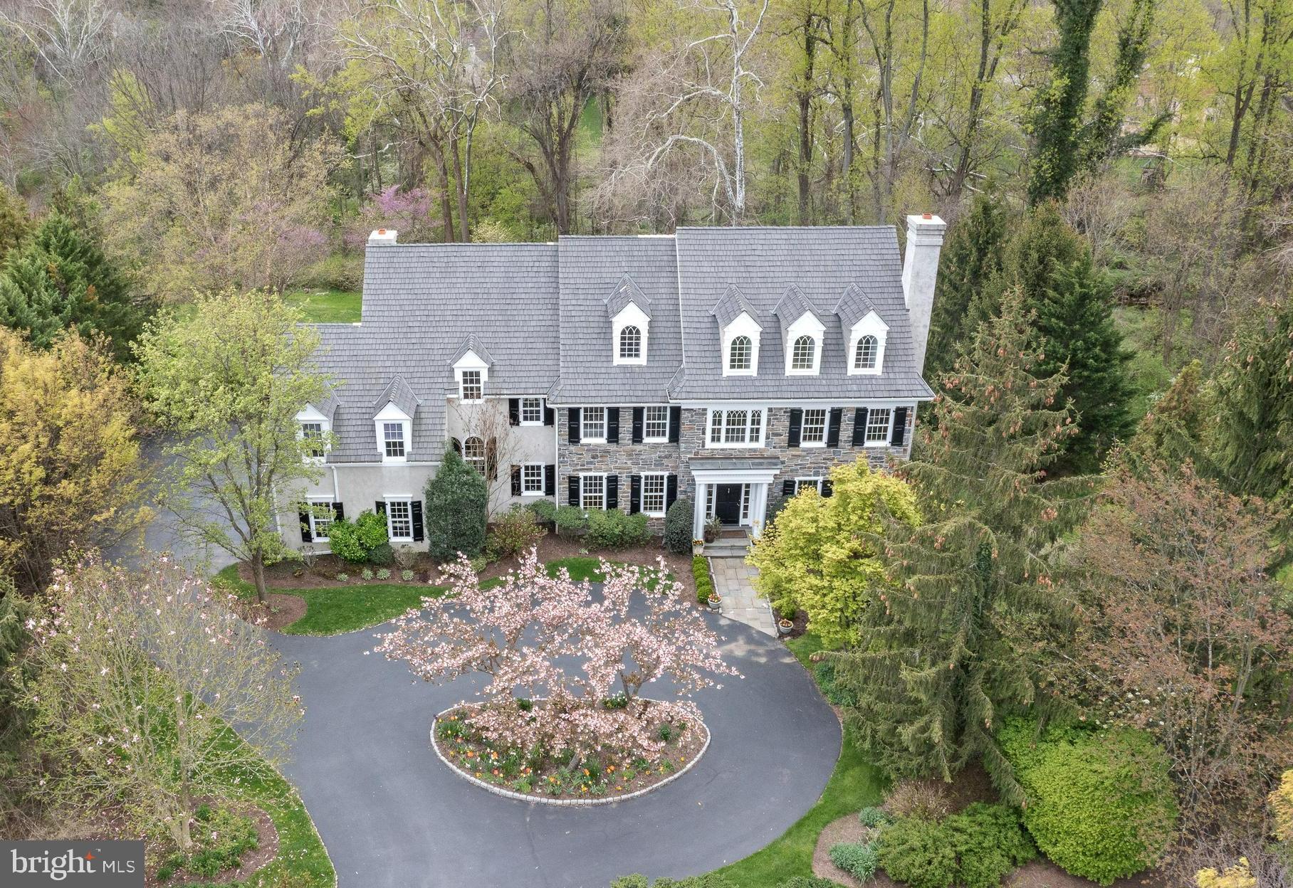 If you've been dreaming of sophisticated yet laid-back living in a renowned community, then you're sure to admire this immaculate home! Located in the sought-after Brooke Farm neighborhood, this home is privately sited, with sweeping 180-degree views of open space and soaring trees in the rear and grassy open space in the front. Visitors to this 4-level home are greeted by a front-to-back Entrance Hall. Extensive millwork and hardwood floors enhance the 1st floor. Floor-to-ceiling bookshelves line the charming Library/Music Room. The spacious Living Room has a wood-burning fireplace and windows on two walls. Elegant dinners await under the classic candelabra-style chandelier in the formal Dining Room near the convenient Butler's Pantry which has separate wine and beverage refrigerators. Expansive glass windows along the entire rear of the house frame the scenic outdoors as you enjoy meals in the Breakfast Room. Renovated for gourmet cooking, the Kitchen is equipped with top-of-the-line stainless steel appliances including a 36” Miele refrigerator, a 36” Miele freezer, two Wolf wall ovens, a Wolf 6-burner gas range with grill, two Miele dishwashers, and two Sub-Zero refrigerator drawers. The natural stone island offers ample room for casual seating and entertaining. There is extensive storage under the island and full pull-out pantry drawers line the kitchen. A coffered ceiling, distinctive fireplace, and wall of windows make the nearby Family Room a wonderful space for casual relaxation.
Immerse in the restful atmosphere of the Master Bedroom retreat with a tray ceiling, gleaming wood floors, a sitting area, and two custom closets. The renovated Master Bath features 2 separate bathrooms adjoined by a glass-tiled steam shower, all with radiant heat in the floor. The steam shower features a heated bench, body sprays and rain shower. Indulge in spa-like relaxation in the large soaking tub after a tiring day. Two more Hall Bedrooms have ensuite baths, while the other two share a large Jack-and-Jill bathroom.
What a delight the 3rd floor is! This expansive Great Room has gleaming wood floors and a separate Meditation Room with Sauna. Great space for a dance or music studio, large office area, hobbies, recreation, or exercise. The walk-in, unfinished Attic has a utility sink, making this level ideal for use as an art studio. Large windows provide stunning views of the rear yard and open space.
The generously sized multi-functional, daylight Lower Level is the ultimate recreational space, with room for ping pong, billiards, and TV watching, as well as a Powder Room and walk-out access to the rear yard and bluestone patio. Walls of closets and a large utility room provide loads of storage. This level also features a light-filled in-law suite, with 6th Bedroom and ensuite 5th full bathroom designed for handicap access, plus a fully-equipped Kitchenette. Another Bonus Room could be used as an Exercise Room, additional Office, or Bedroom with its own ensuite 6th full bathroom.
Host weekend cookouts or enjoy a relaxing nightcap surrounded by picturesque views on the expanded 2-level deck. The beautiful yard features perennials, flowering shrubs, and specimen trees which provide garden interest throughout the seasons. Additional features include a "household command center" desk area near the Kitchen, a large Laundry Room, and an attached, side-entry 3-car garage. Near highly-ranked Radnor Township schools, prestigious private schools, clubs, parks, corporate centers, shopping, restaurants, and train station in the charming village of Wayne. Close to the Radnor Trail, The Willows Park, Chanticleer Garden, and convenient to the Blue Route, Center City, and Airport.
