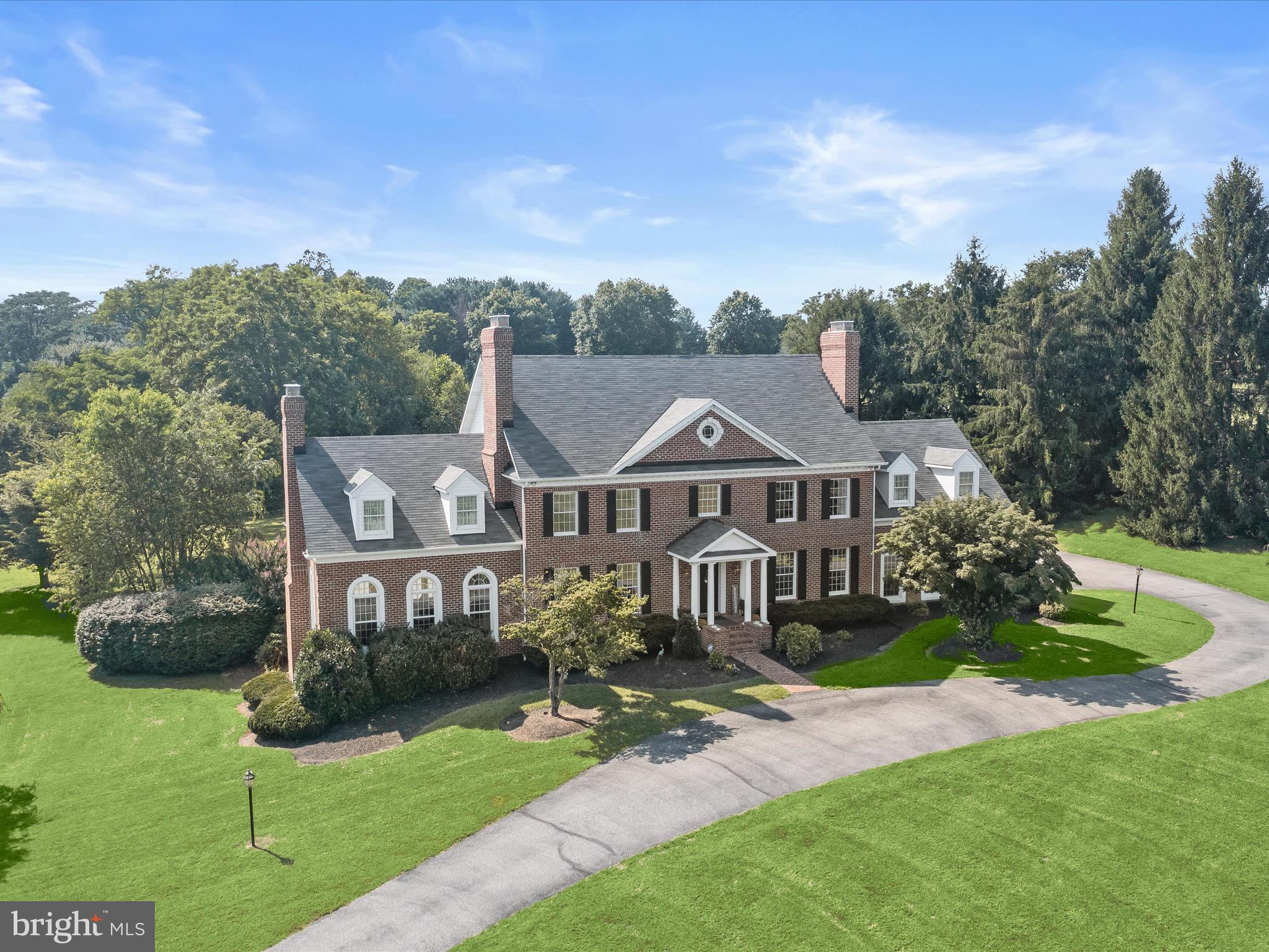 Welcome to this elegant waterfront residence where timeless design meets modern sophistication. Beautifully landscaped grounds and a stream-fed pond set the stage for a grand arrival. Stately columns and a manicured lawn frame the classic façade, offering a glimpse of the refined interiors within.
Inside, the foyer is appointed with dentil crown molding and box wainscoting, custom millwork echoed throughout the main level. The formal living room offers warmth and style with hardwood floors, a wood-burning fireplace, plantation shutters, and sunlit windows. The adjacent formal dining room features another fireplace, detailed millwork, hardwood floors, and a ceiling medallion, all overlooking the lush front lawn.
Designed for entertaining, the chef’s kitchen is outfitted with granite countertops, a KitchenAid island cooktop, peninsula island, double Thermador ovens, Sub-Zero refrigerator/freezer, and a second prep sink in the breakfast area. Just off the kitchen, step into the screened-in porch—an ideal extension of the space and a peaceful spot for morning coffee or al fresco dining. From there, access the expansive 1,000 sq ft deck with integrated propane grill and outdoor kitchen, all overlooking tranquil pond views.
The dramatic, two-story family room impresses with exposed beams, a pellet stove, and Palladian windows that frame the scenery. A custom spiral staircase leads to a loft library, perfect as an executive office with built-in shelving and workspace.
Upstairs, the home’s sleeping quarters are thoughtfully arranged across two upper levels to provide both comfort and privacy. The second floor hosts the luxurious primary suite along with three additional bedrooms and a full bath, while the third floor offers two more spacious bedrooms and another full bath, ideal for guests, extended family, or a private retreat. The primary suite is a true sanctuary, complete with its own fireplace, a serene sitting room, two walk-in closets, and a separate dressing area. The en suite bath is spa-inspired, featuring a soaking tub, custom vanity with built-in shelving, and a personal cedar wood closet. Each of the three secondary bedrooms on this level offers generous space, natural light, and convenient access to the shared bath. On the top level, two additional bedrooms and a full bath provide excellent flexibility for guest accommodations, an au pair suite, or creative studio space.
The finished lower level expands your living space with a large recreation room featuring a sleek electric fireplace and a step-down game room with a full-size bar, perfect for billiards, ping pong, or movie nights.
Function meets flexibility in the oversized three-car garage, which includes a dedicated workshop area and ample storage, ideal for car enthusiasts, hobbyists, or anyone in need of extra space.
Set on over 3 acres, the grounds include a lush lawn, newly planted fruit trees, and access to the scenic, stream-fed community pond, perfect for fishing or quiet reflection. Pond privileges are included.
Recent upgrades include two new HVAC units with 10-year warranties (2025), full interior paint (2023), new carpet (2022), water heater (2019), and a water filtration system (2018). With its luxurious updates, versatile layout, and serene setting just minutes from Baltimore and major commuter routes, this extraordinary estate offers the best of refined country living with everyday convenience.
Note: Select interior photos have been virtually staged.