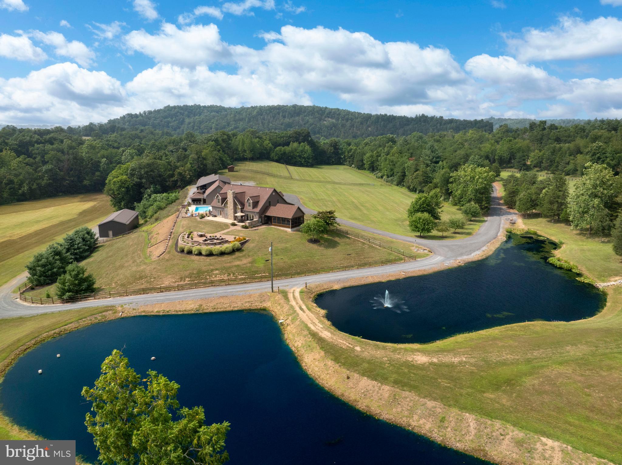 Welcome to your private valley retreat, nestled on 116.5 scenic acres in a peaceful and secluded setting surrounded by rolling ridges. This one of a kind property offers the perfect blend of natural beauty, expansive living spaces, and exceptional amenities. With open fields, mature woods, and abundant wildlife, including deer, bald eagles, wild turkeys, and even the occasional black bear, this is truly a nature lover’s paradise. A key highlight is the serene frontage along Tonoloway Creek, offering endless opportunities for water recreation, fishing, or simply relaxing by the water’s edge. Despite its tranquil seclusion, the property is conveniently located just 5 miles from I-70, providing quick and easy access while maintaining complete privacy. At the heart of the estate is a custom-built, two-story residence featuring 6 spacious bedrooms, 5 full bathrooms, and 1 half bath, perfect for hosting gatherings. The main level is anchored by a two-story great room with vaulted ceilings, exposed wood beams, and a cozy wood-burning fireplace with heatilator, creating a warm and inviting space year-round. The chef’s kitchen is a standout, boasting oak cabinets, quartz countertops, hardwood flooring, stainless steel appliances including a double oven and built-in microwave, and a generous dining area for everyday meals or festive occasions with gas fireplace. Just off the kitchen, a full bath and laundry area offer convenient access to the outdoors. The main-level primary suite includes a luxurious en suite bath with a glass block walk-in shower and recessed lighting. Upstairs, four additional bedrooms feature vaulted ceilings and share two full bathrooms, including a convenient Jack and Jill layout. The fully finished lower level is designed for ultimate relaxation and entertainment, featuring a private guest suite with full bath, a spa-like sauna, a separate walk in shower, and soaking tub, a custom cigar room with French doors, air filtration system, and exhaust, a large theater/media area with built-in speakers and gas fireplace, a billiard/game room perfect for gatherings, and a climate-controlled wine room. A secure hunters room provides additional storage and peace of mind. Step outside to enjoy the beautifully designed outdoor living spaces. A detached screened-in porch with wood-and-beam cathedral ceilings offers a peaceful escape, while the adjacent patio area features a built-in grill and a large fire pit, ideal for outdoor entertaining or unwinding after a long day. From here, take in sweeping views of two private ponds, complete with fountain and stocked with bass, koi, and crappie. Whether you're sipping morning coffee or enjoying a sunset, the outdoor setting is as calming as it is picturesque. Enjoy the heated saltwater pool with fencing, a pool monitor, and a stylish cabana with bar seating, perfect for summer days spent entertaining. Additional buildings include a pool shed, an oversized three-bay garage with loft storage, and a spacious pole building. Equestrian enthusiasts will appreciate the 5-stall horse barn complete with a horse wash bay, tack room with bathroom and mini-split system, and fenced paddock and pasture areas. There’s also a second fenced pasture with a horse run-in, as well as an additional pole building housing an oversized 6-car garage with tall ceilings. Whether you’re looking for a private estate, a working hobby farm, or a serene retreat from the everyday, this extraordinary property offers a rare opportunity to live in harmony with nature, without compromising on luxury, space, or convenience. Don’t miss your chance to experience everything this incredible property has to offer, schedule your private showing today!