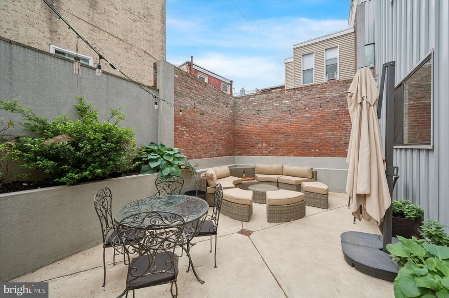 Welcome to an exceptional dream home—a stunning, spacious, urban oasis with six outdoor spaces in vibrant Pennsport! This exquisite property offers an unparalleled living experience with a unique private courtyard, luxurious amenities, and abundant natural light from three sides and via a skylight in the central staircase.

Pull into your deep one-car garage with ample storage space or enter through the front door and foyer to the light-filled sitting room with a large coat closet and a dedicated shoe closet. On this level, the expansive, wrap-around courtyard with its high brick walls, charming garden, and room for entertaining makes you feel like you are in a true oasis.

Up one floor, the stone-tiled wall accompanies you to the main level with open concept living. The gourmet kitchen is a chef’s delight with a 5-burner range, stainless steel appliances, marble countertops, a wine fridge, built-in microwave, pantry, and plenty of cabinets. Enjoy casual meals at the eat-in counter or in the dining area with room for a large formal table. A mini deck off the kitchen is ideal for morning coffee. The living room boasts a stone-tiled gas fireplace, perfect for cozy evenings. The deck off the living room allows for seamless indoor-outdoor living. A half bath is conveniently located on this floor.

The primary bedroom suite occupies the entire third level. Airy and filled with light, this suite includes both a walk-in closet and an additional deep, double, reach-in closet. Indulge in the spa-like primary bath featuring a double sink vanity, massive soaking tub, and triple shower head with a pebble floor. Store all the essentials out of sight in the bathroom linen closet.

Above this, you’ll find two generous-sized bedrooms with matching generous-sized closets. The back bedroom has a wall of picture windows with gorgeous views of the Philly skyline, and the front bedroom has a sliding glass door that leads to its own private deck. The bathroom on this floor has a tub and stone tile. In the hall, the washer and dryer have one closet, and linens have another, to make life easy.

The top-level landing opens to the roof decks and is perfect for setting up a bar with a mini fridge, ideal for entertaining. Yes, decks-plural. Enjoy two spacious roof decks, perfect for relaxing or hosting gatherings with stunning views. Watch the fireworks on the Delaware or over the stadiums.

The basement bedroom suite doesn't feel like a basement at all, thanks to a large window that floods the space with light. It includes a walk-in closet plus a mini bar just outside the bedroom. The bathroom on this level features a large shower with quadruple shower heads. Beyond that is an ample storage space on this level.

With its numerous outdoor spaces, high-end finishes, hardwood floors, recessed lighting, high ceilings, dual-zoned HVAC, and abundant natural light due to the large windows throughout, this home has everything you need for comfortable and stylish living. Don't miss out on the opportunity to make this oasis in the city your forever home!  Plus, there are four years left on the 100% tax abatement!