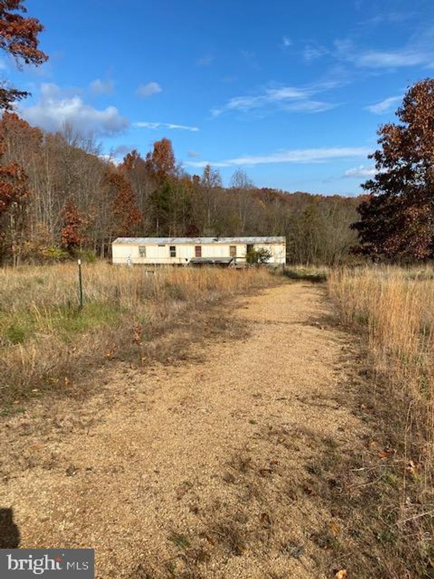 Hard to find,  UNRESTRICTED, private, mostly level, 5.25 acre lot with mountain views. The front of the lot is  mostly cleared with a driveway leading to a mobile home (of no value).  The lot is improved with a well, septic and electric is available.  Buy now and build later.  PLEASE HAVE YOUR HIGHEST AND BEST IN BY 5:00 ON WEDNESDAY, November 30th.