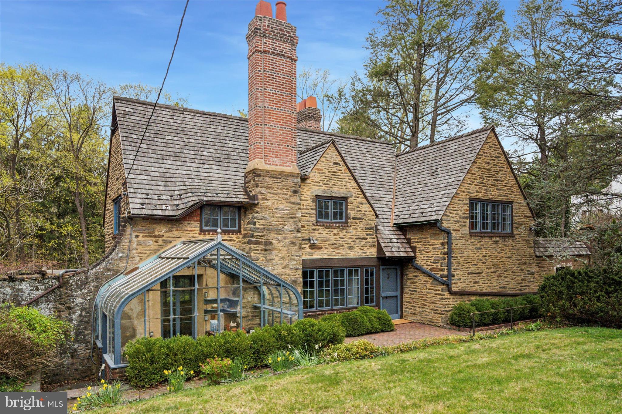 Welcome to this extraordinary property designed by esteemed architects Mellor, Meigs and Howe for Robert T. McCracken, Esq. in 1920 with superb 1926 addition. It is sited on the treasured block of Westview Street with access to the Fairmont Park trail network. There is an understated elegance to the property design that remains timeless: It balances indoor and outdoor living complete with the fully enclosed stone walled garden room with belvedere, pergola and multiple brick and stone walkways and courtyard. There is documented Samuel Yellin ironwork including hardware and braces for multiple doors and windows.
The first floor lends itself to large scale or intimate entertaining and modern convenient living with updated chef’s kitchen with walk in pantry, laundry room and mudroom, family room and large dining room with access to the walled garden and greenhouse. Take the steps down in the conservatory flooded with light by the glass paned wall with fountain and powder room to the incredible living room addition with soaring ceiling and massive stone fireplace, back study and attached shed. The second floor includes a primary suite with updated en-suite bathroom and two more bedrooms with a second full bathroom. Updated systems include cedar roof (approx. 10 years old), electric and central air conditioning. There is a front cobblestone driveway and a two car garage that is accessed from Kitchens Lane at the rear of the property that can be reached through back stairs of the residence.
This property named “Garth”, meaning enclosed garden or yard, began its initial form as a hunting lodge for Mr. McCracken and was later substantially expanded through the 1926 addition. Mellor, Meigs and Howe were awarded the American Institute of Architects, Philadelphia Chapter, Gold Medal in 1922 for the design of the original home: It is considered one of their masterpieces. Come explore the charms of 1009 Westview and make it yours today! One of the owners is a PA licensed real estate broker.