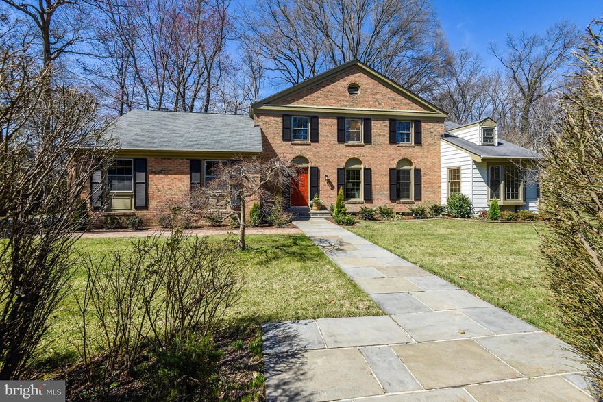 Spacious and gracious, this classic five-bed, four-bath home is a treasure. Step through the apple red front door into the stone-tiled foyer, complete with a large, lighted closet. Note the sight line includes a lovely view through the kitchen and breakfast area to the backyard beyond.   To the right, a large living room beckons with rich hardwood flooring and near floor-to-ceiling windows. Beautiful wood double doors lead to a serene family room with an exposed brick wall, vaulted ceiling and skylight, and a beautiful bay window overlooking the private front yard. Perfect for an office or a quiet spot to read, paint, write, or nap. Adjoining the sitting room through louvered French doors is a main-level bedroom with a pair of handy built-ins and a full bath.  Off the living room is the generous dining room, roomy enough to fit a large table and plenty of seating; large windows open up to the green backyard. The space flows into the den facing the backyard, anchored by a beautiful rustic fireplace. Numerous and varied windows, including skylights, bathe the space in natural light, and two separate doors open to the deck outside.  Warm and welcoming, the kitchen features two sinks, granite counters, loads of usable storage space in solid wood cabinets and pantries - plenty of space for a large table. Stainless steel appliances include a backsplash that sits over the gas stove and a new range hood. There are two ovens in here in addition to an oversized refrigerator, all ready for entertaining family and friends. A passthrough window over the sink connects to the camaraderie and conversation in the den.  On the other side of the kitchen is the powder room as well as a second living room with a wood-burning fireplace, charming bead board paneling, another closet, and access through French doors to the large deck outside.   Upstairs, the hallway leads to three bedrooms, a linen closet, a full bathroom with a double vanity next to a unique glass brick light well and skylight. The primary bedroom is a spacious haven that spans front to back with a comfortable sitting area overlooking the front yard below. The primary bathroom includes a double vanity, a separate tub and shower, toilet and bidet. Wait till you see the bonus step-up room with a huge walk-in closet and dressing area that also offers a built-in, fold-out ironing board. Also on this level is convenient access to generous attic storage. Downstairs, the basement has the laundry room, utilities, storage closets, a bonus room and full bath.   Running the length of the house in the back, a comfortable deck with charming pergolas and lattice work offers privacy and plenty of room for living and dining, with the yard surrounded by tall trees and mature landscaping. A double garage offers more storage and convenient access to the first floor.  Located on land that was originally part of George Washington’s farms, this home is close to public transportation, shopping, the Potomac River, Old Town Alexandria and all the amenities of Washington, DC.