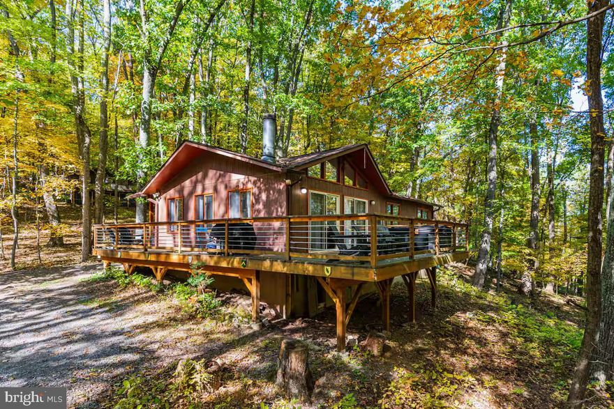 Recently renovated, Nordic-style chalet cabin located in the Coolfont community of Berkeley Springs!  This home features a spacious wraparound porch with modern finishes throughout, including an open-concept kitchen complete with natural wood cabinetry, a breakfast bar, wood stove for cozy winter nights (in addition to electric heat), vinyl plank flooring in the main living areas, and berber carpet in the bedrooms.  Professionally designed with all new furniture, modern decor, and hot tub.  The seller spent over $36,000 upgrading the property.  As a vacation rental it has generated $176,000 over the past 36 months (over $50,000 annually), and can come with an existing property manager and cleaner. This cabin is located in the Coolfont Mountainside community, with an outdoor community swimming pool, tennis & basketball courts, & hiking trails – and is a short 10-minute drive from downtown Berkeley Springs.  Hot tub and furniture optional, available for purchase.  See seller docs for a summary of rental history and financials.  $1,000 buyer credit if you continue using the same property manager.  Perfect vacation home or investment property!