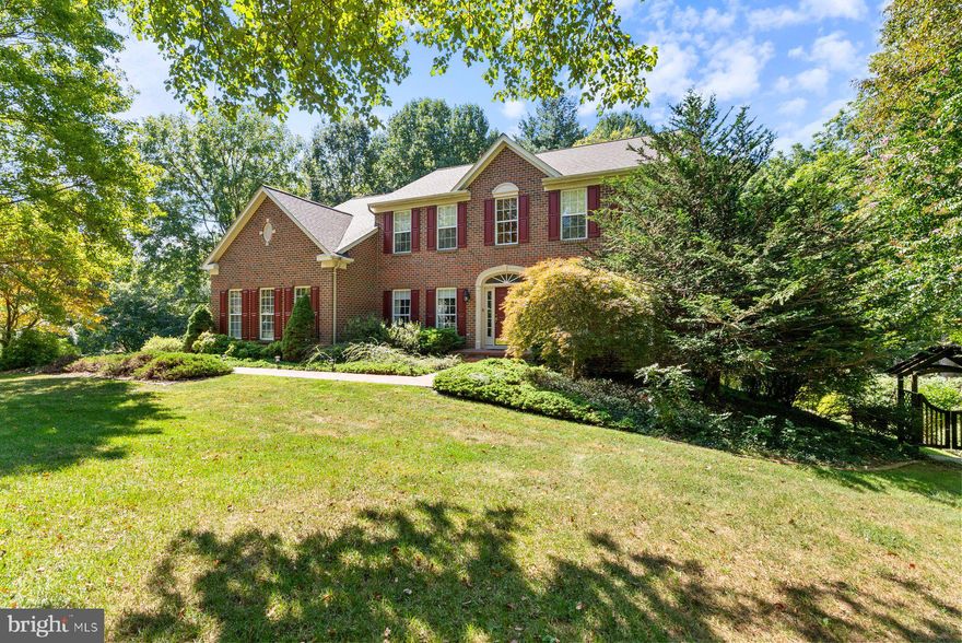 Incredible opportunity to live in the wonderful community of Sumner's Hollow on a gorgeous 2-acre lot with privacy galore!  This property is a rare gem offering wonderful space and a backyard sanctuary like no other!! This meticulously maintained brick-front colonial is gracefully situated on a picturesque 2-acre corner lot. A charming brick walkway leads you to the elegant entrance, setting the tone for this beautiful property. The main level offers a dramatic 2 story foyer, private office with double doors, a formal living room, and a spacious dining room. The kitchen is designed for both everyday living and entertaining. It features a spacious island, sleek quartz countertops, under counter lighting, gas cooking, table space, pantry and ample cabinetry for storage. The open layout flows seamlessly into the sunlit morning room, where sliding glass doors lead to a low-maintenance deck with retractable awning—perfect for indoor-outdoor gatherings. The adjacent family room boasts a cozy gas fireplace, creating a warm and inviting space.  The main level laundry and powder room add extra convenience to this level. Upstairs, the spacious primary suite includes a large walk-in closet, an additional closet, and an en-suite bath with a corner soaking tub, separate shower, and 2 separate vanities. Three additional spacious bedrooms and a full bath complete the upstairs.  The finished lower level offers another full bath, generous storage areas, workshop, and an expansive L-shaped recreation room with walk-out access to the extraordinary backyard. A charming additional room with access to outside is currently using as a potting room and is a quaint and creative space for gardening enthusiasts but can also be used to suit your needs. Step outside to discover one of the crown jewels of this property - the exceptional backyard oasis. Thoughtfully designed to inspire peace and connection with nature, this outdoor haven features lush landscaping, tranquil Zen Garden, water features, pergola with a swing, whimsical shed with an arched doorway, and elements like lighting and shade to create a peaceful retreat away from the daily hustle and bustle. Meandering walkways and a decorative bridge connect the beautifully landscaped garden areas. The back of the yard also offers a large open space —perfect for gatherings, games, or outdoor activities. A spacious side-entry two-car garage is complemented by an expansive driveway, offering generous parking for multiple vehicles. Recent updates include a brand-new Hot Water Heater, Quartz Countertops in Kitchen, Roof (7 years) HVAC - (5 years), Washer/Dryer (2 years) Great location - this home offers you the feeling of getting away from it all yet is close to commuter routes and great amenities like Piney Run Park & Downtown Sykesville! Welcome Home!!