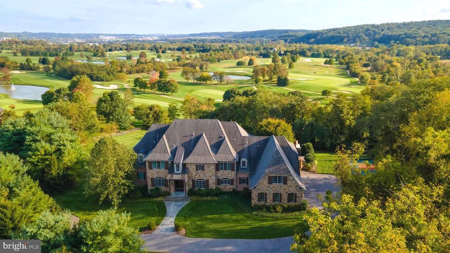 Overlooking the 5th tee of Hayfields Championship Golf Course, this enchanting French country home beckons you with its timeless charm and elegance. With over 14,000 total square feet, this is not just a residence but a destination for extraordinary celebrations, unforgettable gatherings, and a life of luxury, privacy, and tranquility. The desirable Hayfields Manor community is in the epicenter of convenience and accessibility. Be greeted by the grand two-story foyer with a curved stairway and hand-crafted wrought iron stair railing, crafting the grandeur and sophistication ahead. Reclaimed hardwood floors, high ceilings, expansive windows, extensive millwork with arched doorways, beautiful crown molding, and tray ceilings; you will find intricate architectural details throughout the entire home. The expansive open-concept living area encompasses an elegant formal dining room boasting a remarkable wet bar. It ensures impressive and seamless entertaining with a stamped copper sink, generous counter space, and a Sub-Zero wine fridge. The combination living room, great room, and gourmet kitchen are inviting with large, bright windows for gorgeous views of the golf course and numerous access points to the elevated bluestone terrace. Numerous gas fireplaces with stone wall backdrops offer a cozy ambiance, while the state-of-the-art sound system ensures music sets the mood. Whether you enjoy the glow of the morning sun or the serene hues of dusk, this area embraces the changing light of each day. The gourmet kitchen is a chef’s dream, with top-of-the-line appliances, a panel-covered Sub-Zero refrigerator, a large island with counter-seating a farmhouse prep sink, and a walk-in pantry. Experience remarkable practicality and comfort with dual home offices, sizable laundry rooms on the first and second floors, and not one but two primary suites. The upper level features a second primary suite with a luxury bath, and three bedrooms each offering access to their private baths. A centralized sitting area overlooks the great room and the expansive recreation room has a full bar, game area, and television room. Travel to the home’s lower level to find the well-appointed retreat that caters to your every need. With a full bar, a charming pub space, a wine cellar, a deluxe 11-person movie theater, a cozy sitting area with a gas fireplace and a stone accent wall, a sizable bedroom, and a full bath, this lower level is the epitome of relaxation or hosting and toasting with family and friends. The outdoor living spaces are spectacular and complete with a sports court, hot tub, a magnificent wood-burning fireplace with pizza oven, and an outdoor kitchen with sink, grill, and counter seating for six. The bluestone terrace extends the length of the home to accommodate both dining and lounging. The wood ceiling with lighting protects against the bright sun by day or illuminates the party at night.  Appreciate the captivating vantage point of the terrace as you gaze upon the pristine front nine holes of the golf course or witness the enjoyment unfolding in the saltwater in-ground pool. What more could you want? An irresistible fusion of sophistication and relaxation, this home is a must-see!