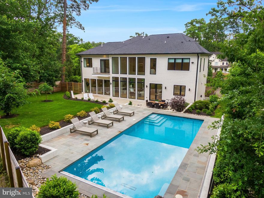 Privacy, security and modern luxury come together in this award-winning home in sought-after Chesterbrook Woods. Sitting on a stunning lot of nearly one half acre, this 6BR, 6BA masterpiece was designed to maximize natural beauty while delivering every high-end feature you could want. A gate and a fully fenced yard (front and back) has been added for enhanced privacy and security, setting the tone for what’s inside.

From the 3-car garage and elevator to the heated pool with an automatic cover, every detail has been thoughtfully considered. The home is flooded with natural light thanks to floor-to-ceiling windows throughout, and it even includes solar panels with two Tesla battery packs—a rare and valuable feature.

The gourmet kitchen is a showstopper, with quartz countertops, a massive waterfall island with seating, high-end stainless-steel appliances, and a sleek modern pantry. The two-story great room, with its soaring 20-ft ceiling, exposed upper-level library, and double-sided gas fireplace, is as impressive as it gets. The open-concept formal dining area is wrapped in glass, opening to a covered balcony and an outdoor viewing deck.

The primary suite is its own retreat, featuring two walk-in closets, a private balcony, a gas fireplace, and a spa-like bath. Three additional bedrooms, each with en-suite baths, offer space and style. The walkout lower level is built for entertaining, complete with a guest suite, fitness room, theater room, and an incredible wet bar/wine room/lounge. Step outside to the private front deck oasis with a built-in gas fire pit.

Every inch of this home is designed with high ceilings, hardwood flooring, modern lighting, and incredible spaces. Located minutes from McLean’s parks, shops, restaurants, and major commuter routes, this home offers a rare combination of luxury and convenience.

If you're looking for a home that stands out in every way—this is it.