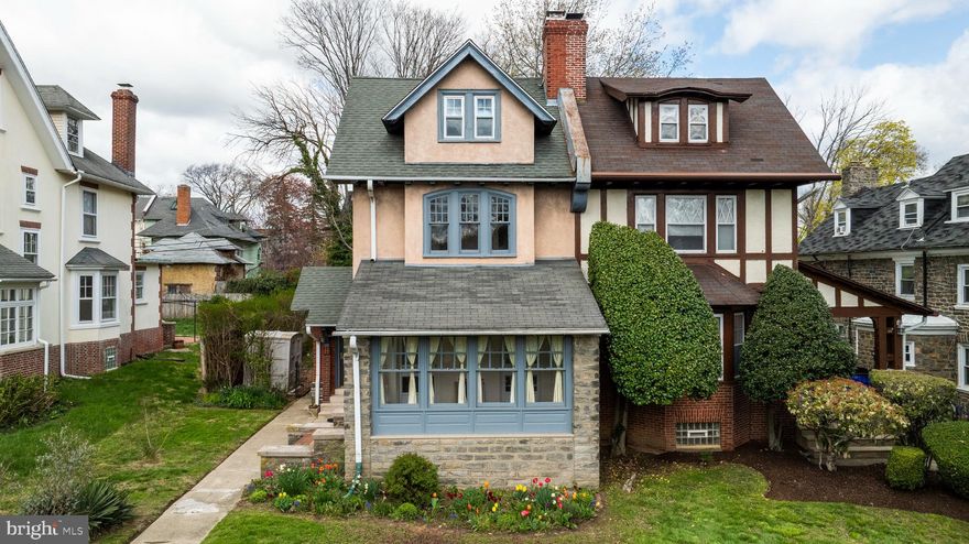 Welcome to 6325 Woodbine Avenue, a spacious and lovingly maintained twin home tucked into the heart of Philadelphia’s historic Overbrook neighborhood. Full of timeless charm, this beautiful residence showcases original woodwork, hardwood floors, and classic architectural details throughout. Set on a picturesque, tree-lined block, you’re first welcomed by a large enclosed front porch and a vibrant garden blooming with mature, native plantings. Step through the original foyer into a warm, inviting living room featuring large windows, built-in shelving, glass doors opening to the front porch, and a cozy gas fireplace. Just beyond, the bright and generous dining room offers a stunning built-in and ample storage—perfect for hosting holiday gatherings or everyday meals. The thoughtfully renovated kitchen is the heart of the home, boasting abundant cabinetry, expansive stone countertops, and a smartly designed island—ideal for cooking, entertaining, or casual dining. From the kitchen, step out onto a small rear porch that leads to a deep, sun-filled, fenced-in yard complete with lawn, native plantings, mature trees, and garden beds. It’s an ideal space for outdoor dining, entertaining, or simply relaxing in your private green oasis. The large, clean, unfinished basement adds exceptional bonus space with room for a home gym, workshop, or storage. It also includes the laundry area and a convenient half bath. The second floor offers three spacious bedrooms and a full bathroom, all filled with natural light and offering generous closet space. On the third floor, you’ll find three additional bedrooms and another full bathroom featuring a stunning marble sink—ideal for guests, home offices, or creative studios. With easy access to City Line Avenue, 76, St. Joseph’s University, the Main Line, and Center City, 6325 Woodbine Avenue is a rare blend of historic character, thoughtful updates, and unbeatable location.