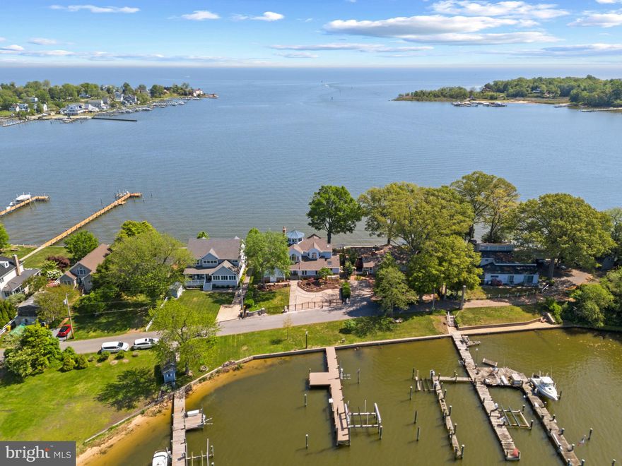 PRICED TO SELL! Panoramic water views across Bodkin Creek out to the Chesapeake Bay from almost every room of this fabulous Poplar Ridge home AND unobstructed sunset facing views of Main Creek. A multitude of upgrades have been implemented throughout the home including new paint inside and out, refinish hardwoods and new flooring, new roof and skylights, gated entry and much, much more. See Improvements list in Documents for all the details. This is a truly unique property with waterfrontage at the front and rear of the home that embraces waterfront living at its best.  The 3rd floor lookout tower with balcony  is a nature lover's dream and provides a one of a kind perspective.  From the moment you walk into the home the views of the water captivate you and the open floor plan flows from the Gourmet Kitchen to the sunken Living Room with awe-inspiring stone fireplace to the Great Room with wet bar, all with beautiful open water views and a great layout for entertaining. The main level accommodates a variety of living styles with a designated home office, guest room (2nd Primary suite) with beautiful ensuite bath and additional bedroom with completely remodeled hall bath. The upper level boasts a spacious Primary bedroom suite with wall of windows and cozy window seat to enjoy the panoramic views of the water, a large walk-in closet and spa-like bath. The sitting area overlooks the foyer and Living room and leads to the additional Bedroom ensuite.  Head up the spiral staircase to experience the lookout tower; perfect for bird-watching, spotting cruise ships on the Bay, or enjoying the sunrise and sunset views. The private deep water pier (6 ft MLW) is located on protected Main Creek. The pier has been upgraded with new top of the line boat lift and jet ski lift, new PVC decking and new electrical and plumbing; just to name a few. The new and improved set up is perfect for the boating enthusiast. The convenient proximity to the Chesapeake Bay will make you the envy of all your mariner friends. Welcome Home!