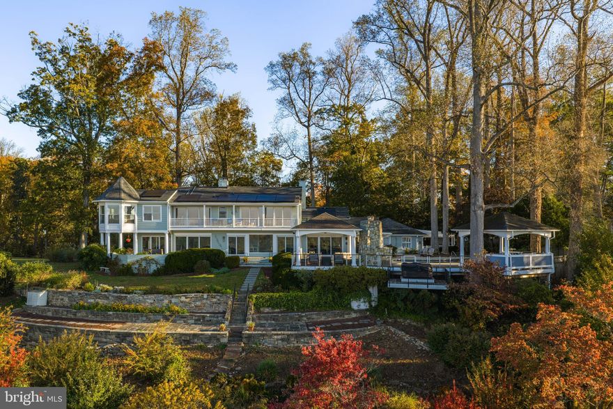 Welcome To 11510 Springridge Road, an extraordinary property offering unobstructed, year-round views of the Potomac River—an exceptional find in the Washington, DC area. This nature lover’s paradise is set on over three acres, adjacent on two sides to the bucolic C&O Canal National Historic Park, with 270-degree river frontage and creek access from which you can float your kayak under the canal and out to the Potomac. This remarkable setting provides a rare opportunity for breathtaking panoramas and a natural sanctuary complete with nesting bald eagles and blue herons for neighbors.
The four-bedroom residence is gracefully perched atop a gentle knoll, where a circular drive with a water feature inspired by the river frames a broad lawn accented by stonework and mature plantings. From the front entry, the eye is immediately drawn to uninterrupted views of the river. Designed to capture its setting, all principal rooms face the Potomac through expansive floor to ceiling windows.
The main level showcases a gourmet kitchen adjoining a gathering room featuring a fireplace and that opens to an extensive outdoor living area including an expansive patio featuring an inground pool and two pergolas. A spacious dining room with built-in glass-front cabinetry and a dual-sided fireplace connects seamlessly to the formal living room, where walls of glass share the warmth of the same hearth. The chef’s kitchen is equipped with double wall ovens, two dishwashers, a Sub-Zero refrigerator and freezer, a Gaggenau cooktop with built-in grill, two skylights, extensive cabinets and multiple pantries, and granite counters. This level also offers an en-suite bedroom, a handicap-accessible full bath, an additional bedroom with hall bath, and a mudroom/laundry with exterior entry and garage access.
The upper level hosts two en-suite bedrooms, including the palatial primary suite. This remarkable retreat features a sitting room, a fireplace framed by custom built-ins, and an octagonal turret. It also offers two voluminous walk-in closets, an additional deep closet, recessed lighting, and both front and rear balconies. The spa-like primary bath includes a glass-enclosed shower, soaking tub, oversized vanity, and skylight, with a convenient storage room just beyond. Both bedrooms enjoy the rare luxury of waking up each morning to glorious water views, often accompanied by majestic eagle sightings.
The outdoor spaces are equally impressive, with sweeping terraces and patios extending across the home—each capturing captivating views. The pool area is complemented by a completely outfitted outdoor kitchen with Viking appliances, a stone fireplace, and two covered pergolas. A hot tub is perfectly perched at the edge of the hill, offering incredible vistas and star gazing galore. Meandering footpaths weave through the lush grounds, leading to secluded perches alive with flowers, birds, and butterflies.
Practical features include a new roof, two propane systems, owner-owned solar panels, a new shed, a potting area, a comprehensive irrigation system, a garage, and a carport.
Whether enjoying the views from inside or out, let nature nourish your soul while still being less than ten minutes from Potomac Village’s shops and restaurants, with direct access to River Road and easy reach of Washington, DC’s vibrancy. Just steps from the Potomac River and near Blockhouse Point Conservation Park and trails, this property blends rare natural beauty with unmatched convenience.