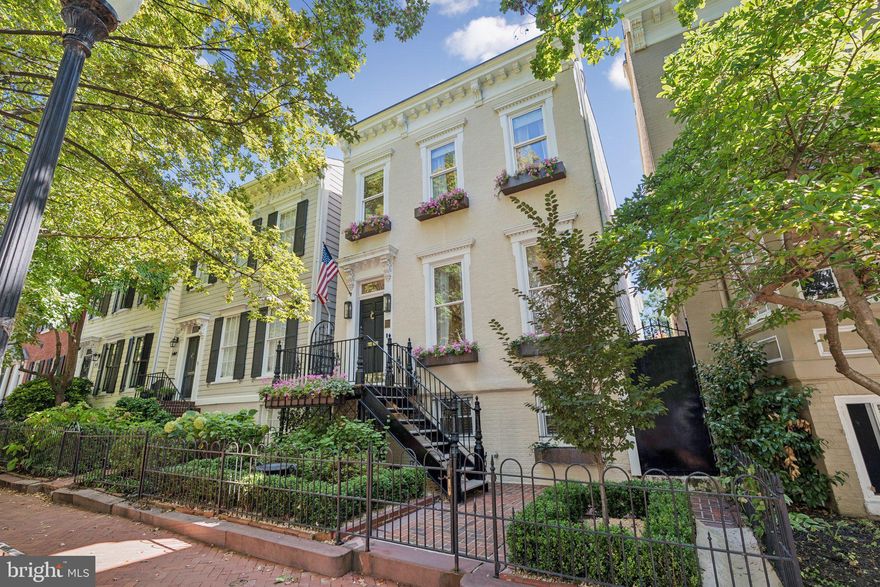 This spectacular, partially detached Federal-style residence, ideally situated on a picturesque tree-lined street in Georgetown's coveted West Village, seamlessly blends historic charm with sophisticated modern updates. Originally built in 1850 and fully renovated in 2020 — with continued thoughtful renovations and upgrades in recent years — this 4 Bedroom, 4.5 Bath home offers approximately 3,110 square feet of beautifully finished living space and garage parking. Showcasing exceptional curb appeal, the residence welcomes you into a sun-filled Formal Living Room and Dining Room, gracefully separated by French sliding glass doors. Both rooms feature gas fireplaces, custom crown moulding, custom built-ins and designer lighting. A comfortable, light-filled Family Room offers a custom hidden storage closet and access to the private backyard space, featuring low-maintenance artificial turf, perfect for effortless outdoor enjoyment. Enter through the elegant arched doorway to a bright and spacious eat-in Kitchen outfitted with high-end appliances, including a Wolf range, an additional in-wall oven, a wine fridge, and a wet bar with a second sink; ideal for entertaining. Ascending to the Upper Level, 3 generously sized Bedrooms await, each including an en-suite Bath. Of the three is the luxurious Primary Suite, offering a walk-in dressing area and a spa-like, Primary Bath with dual vanities, a glass-enclosed shower, a large soaking tub, and heated floors. The finished Lower Level provides flexible living space with a private entrance, a spacious Bedroom, a full Bath, and a full-size Laundry Room alternatively plumbed for a Kitchenette, ideal as an Au Pair or Guest Suite. Modern conveniences include an on-demand tankless water heater, Lutron smart lighting system, Sonos interior and exterior sound system, video doorbell security system, a new smart washer and dryer, and front yard irrigation.  Every inch of this remarkable home has been thoughtfully curated for modern living while honoring its rich Georgetown heritage. A truly rare offering that combines historic elegance with modern luxury — this is Georgetown living at its finest.